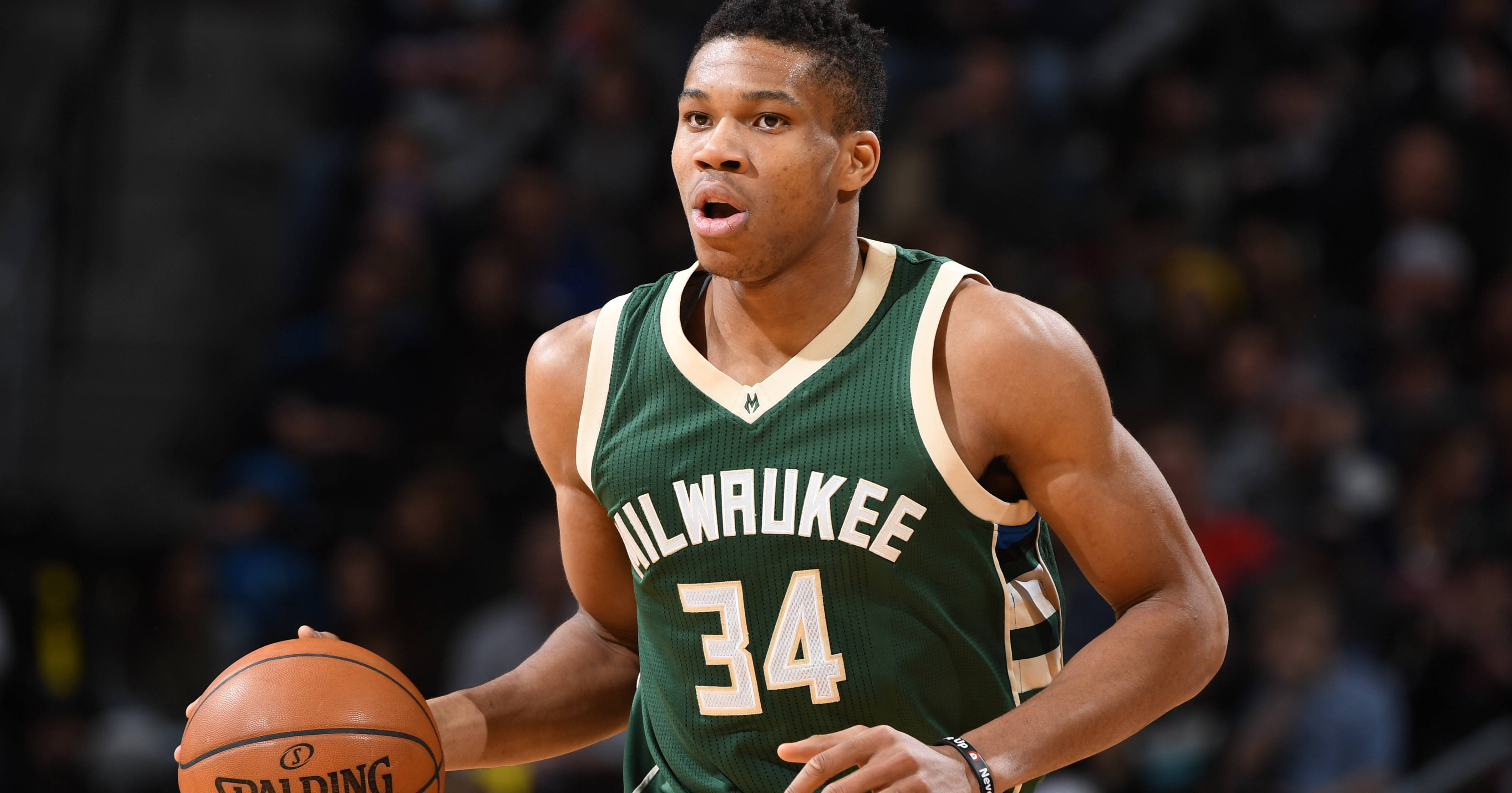 Giannis 桌布 壁紙 — 一位身穿綠色34號球衣的密爾瓦基公鹿隊籃球運動員在場館燈光下進行激烈比賽時運球。