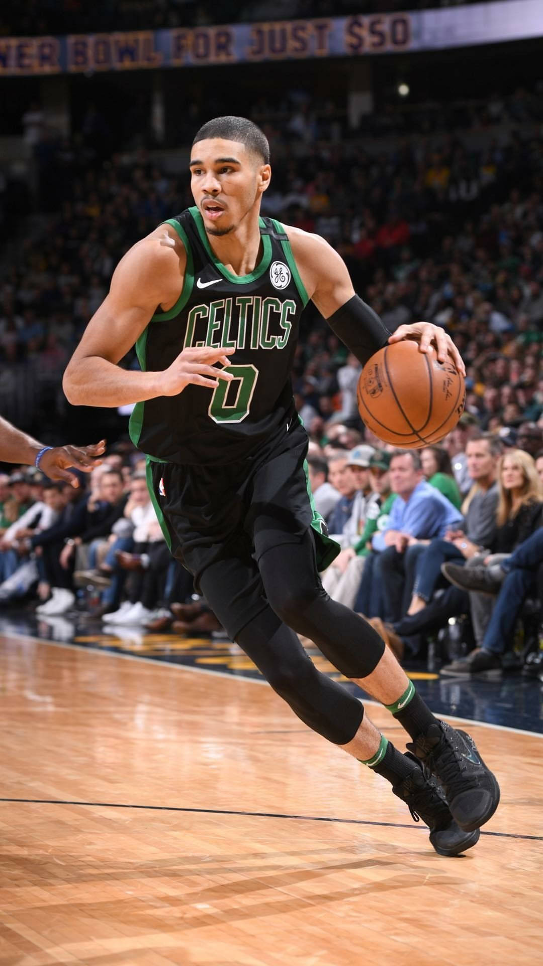 Jayson Tatum 桌布 壁紙 — 一位身穿綠色和黑色球衣的波士頓塞爾提克籃球運動員在激烈的比賽中運球，背景是擠滿的人群。