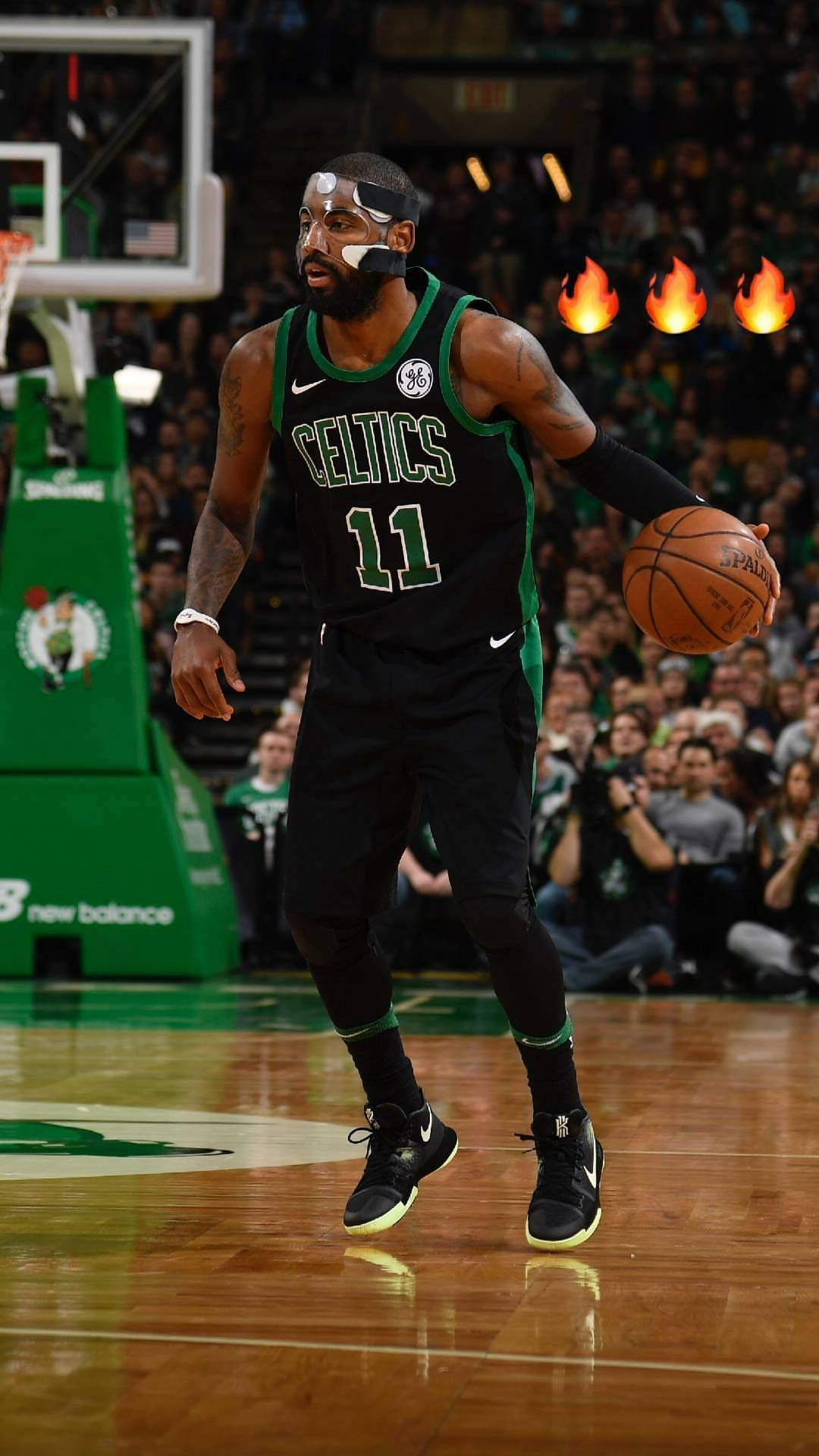 Kyrie 桌布 壁紙 — 一位身穿綠色和黑色球衣的波士頓塞爾提克籃球運動員在場館燈光下進行激烈比賽時運球。