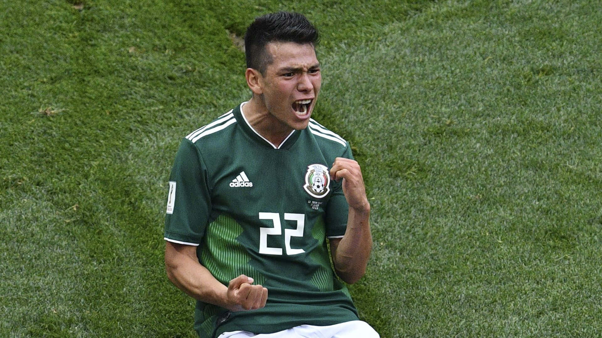 Mexican 桌布 壁紙 — 一位身穿綠色球衣22號的墨西哥足球運動員在充滿活力的綠色草地上熱情慶祝，握緊拳頭，張開嘴巴。