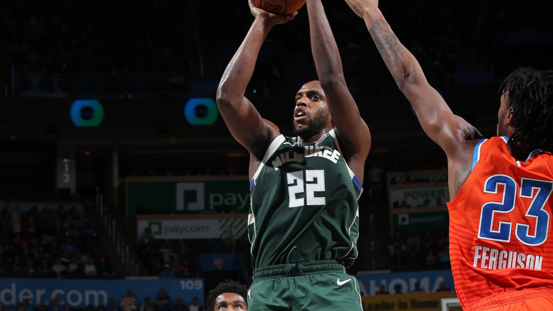 Khris Middleton 桌布 壁紙 — 一位身穿綠色球衣22號的密爾瓦基公鹿球員跳起投籃，而身穿橙色球衣23號的對手則激烈防守。
