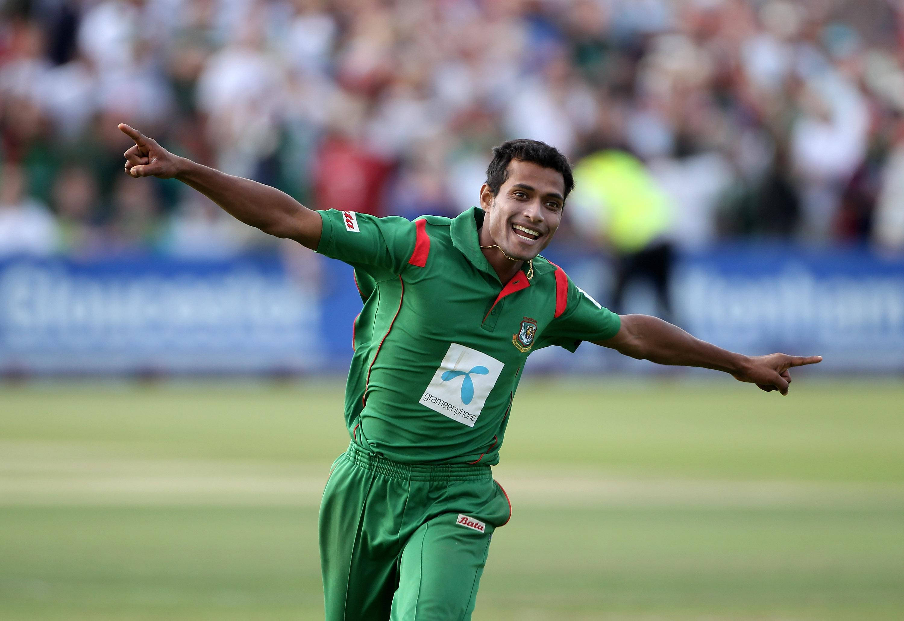 Bangladesh Cricket 桌布 壁紙 — 一位身穿綠色球衣的快樂板球運動員在陽光明媚的球場上張開雙臂慶祝。