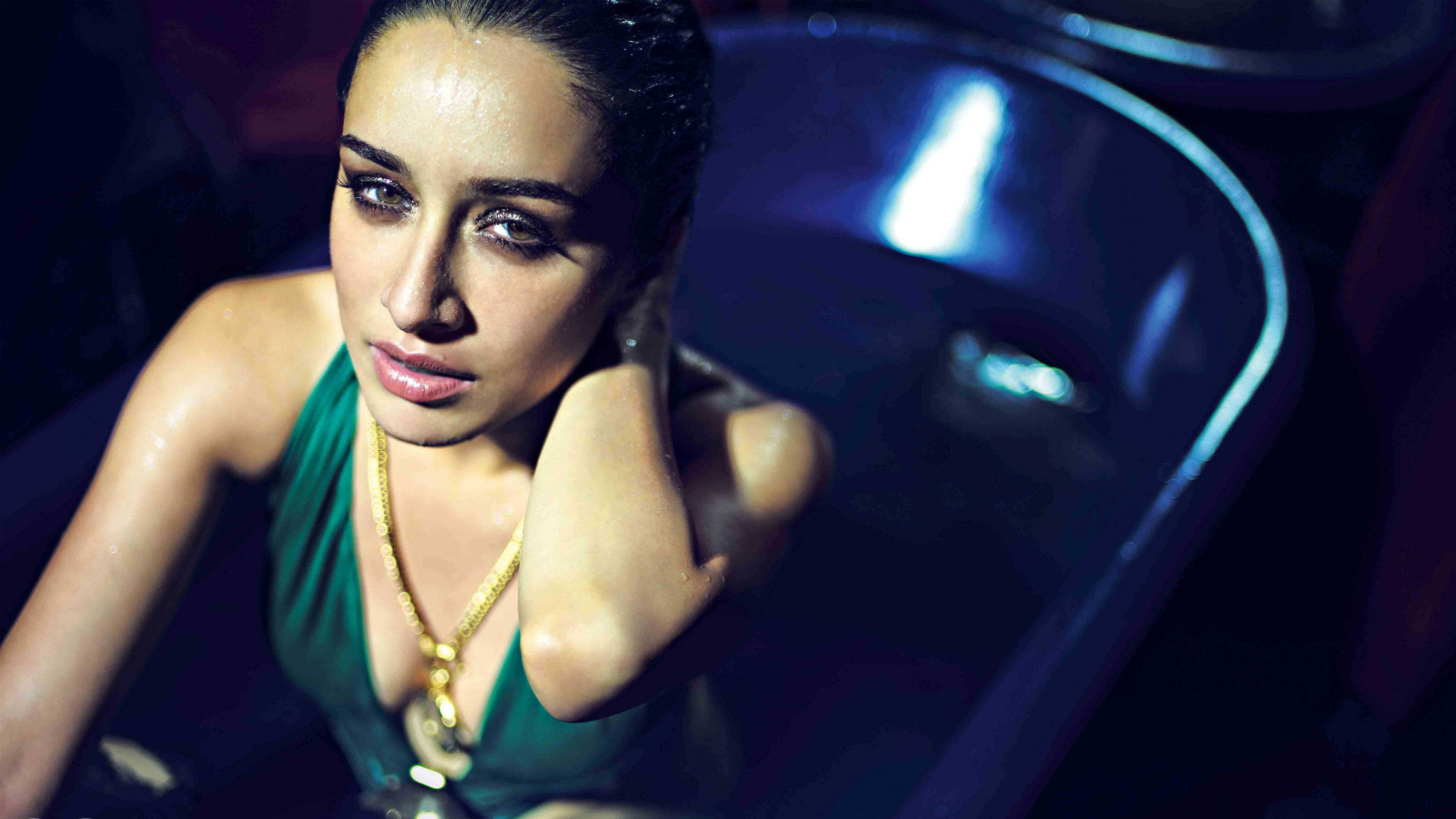 Shraddha Kapoor 桌布 壁紙 — 一位身穿綠色連衣裙和金色項鍊的女性在戲劇性燈光下從深藍色浴缸中向上凝視。