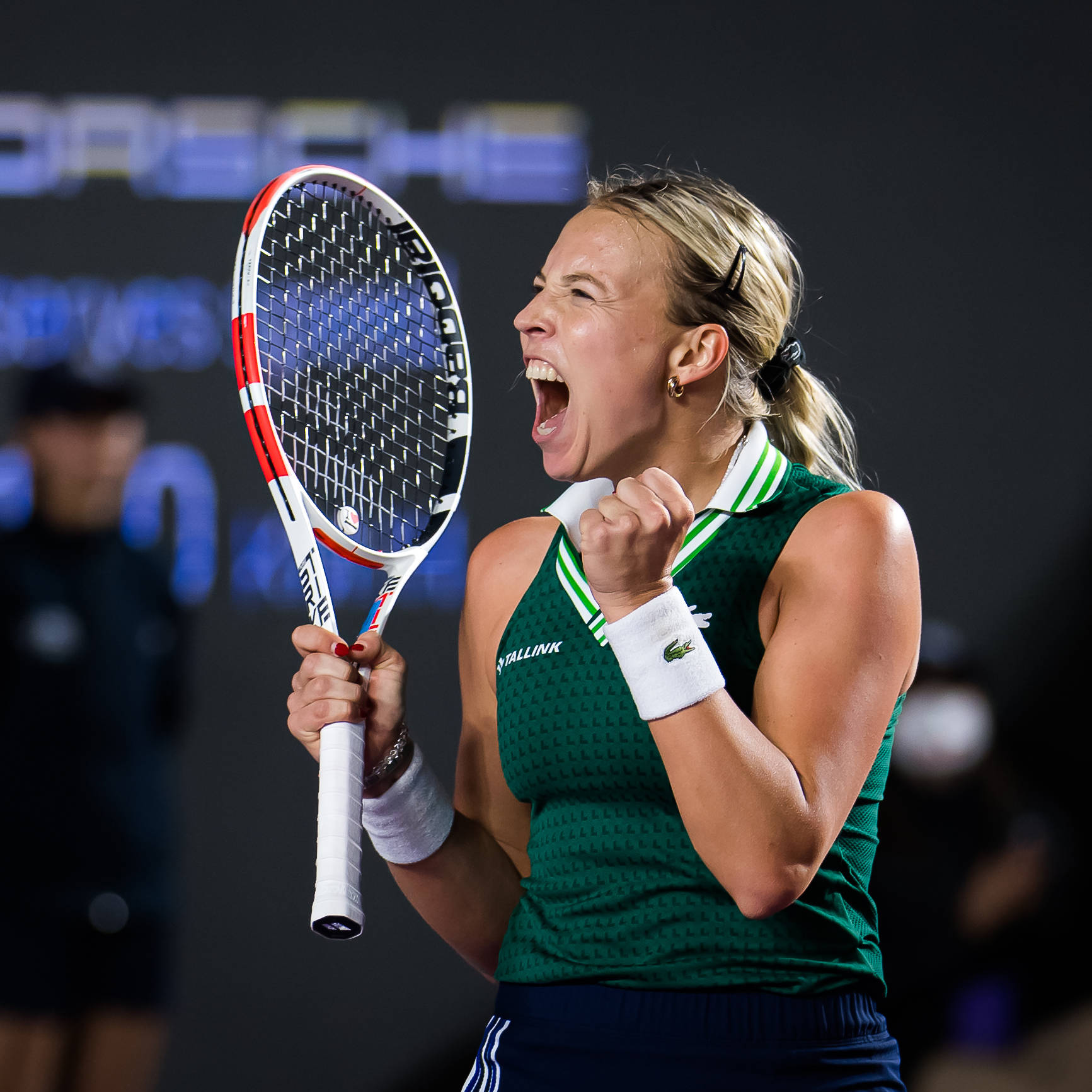 Athletic 桌布 壁紙 — 一位身穿綠色運動服的女網球運動員在深色背景下高舉球拍、握緊拳頭，勝利地慶祝。