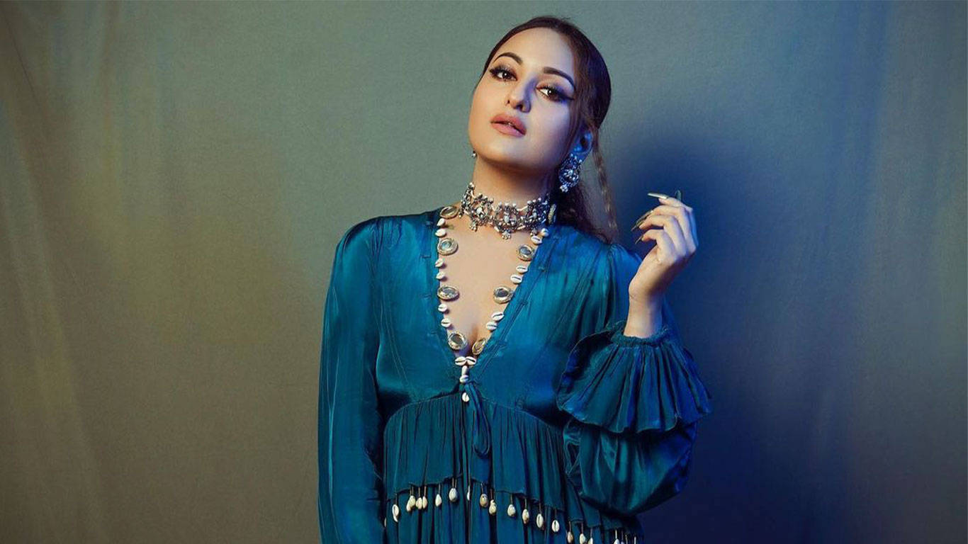 Sonakshi Sinha 桌布 壁紙 — 一位身穿綴有貝殼裝飾的藍綠色絲綢連衣裙的女性，在柔和的漸變背景前優雅地擺姿勢。