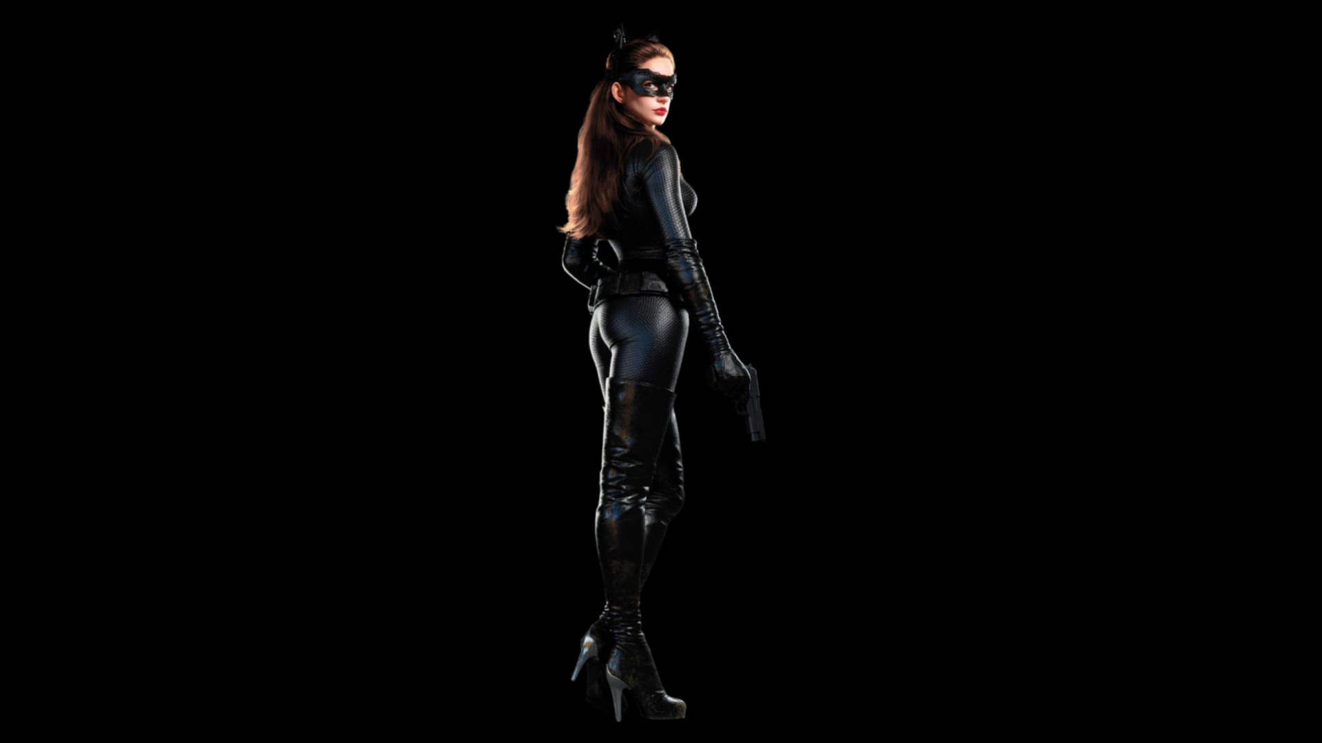 Catwoman 桌布 壁紙 — 一位身穿緊身黑色貓女裝和面具的女性，在純黑色背景下，手持槍支和高跟鞋擺出姿勢。