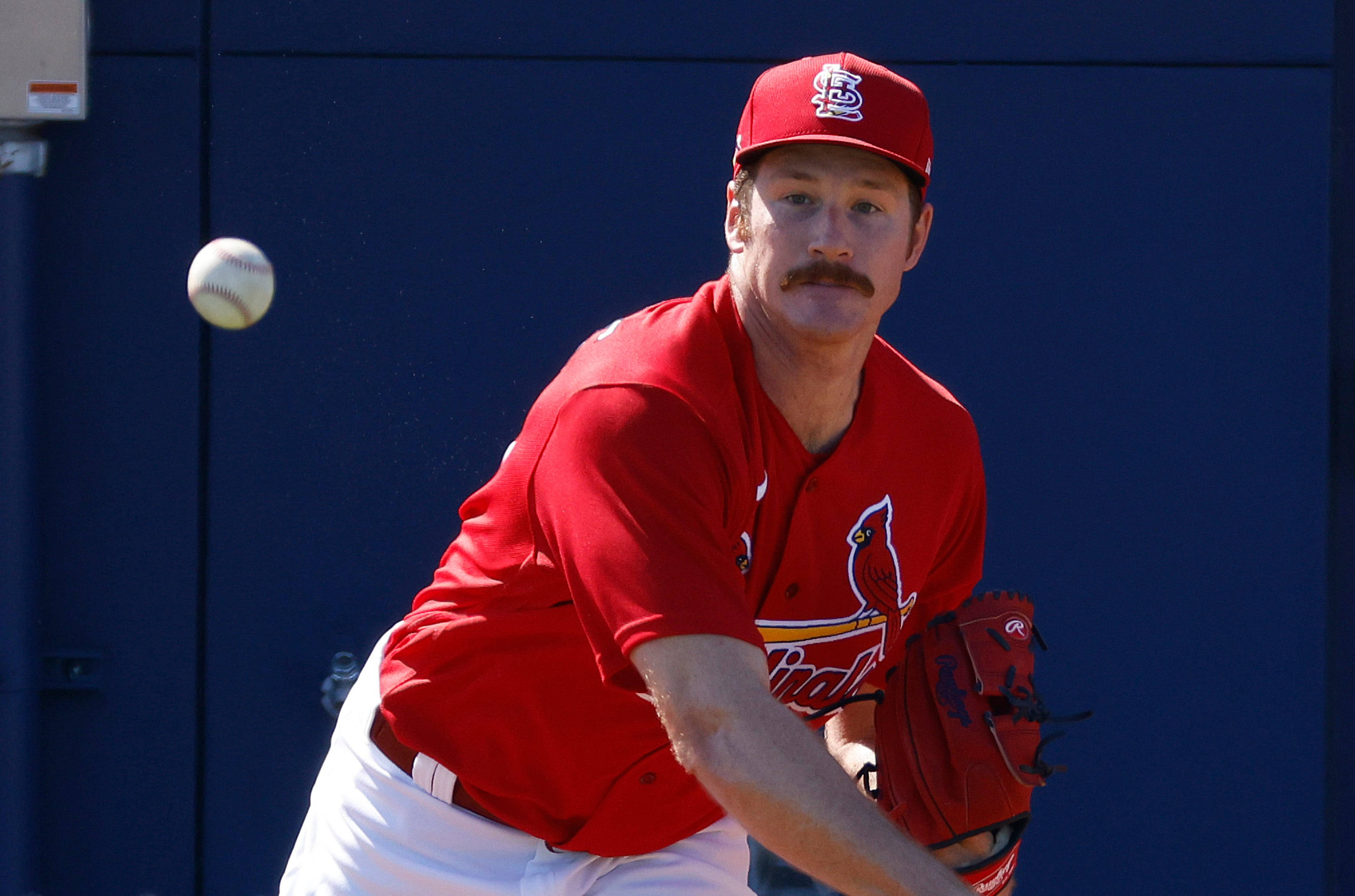 St Louis Cardinals 桌布 壁紙 — 一位身穿聖路易紅雀隊紅色球衣的棒球投手，正對著純藍色牆壁投球。