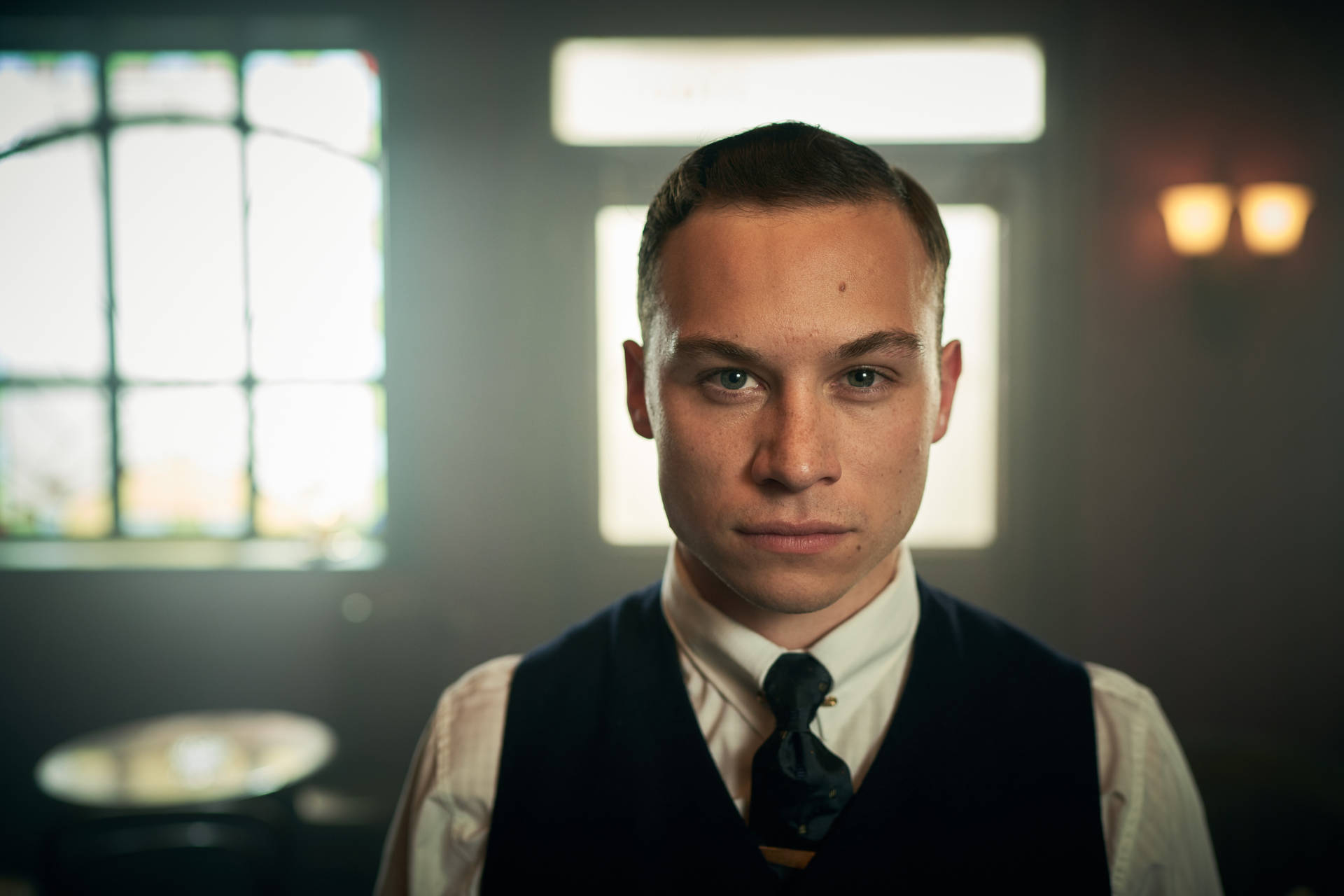 身穿背心打領帶的年輕男子在昏暗的房間裡直視相機。 — Peaky Blinders 壁紙