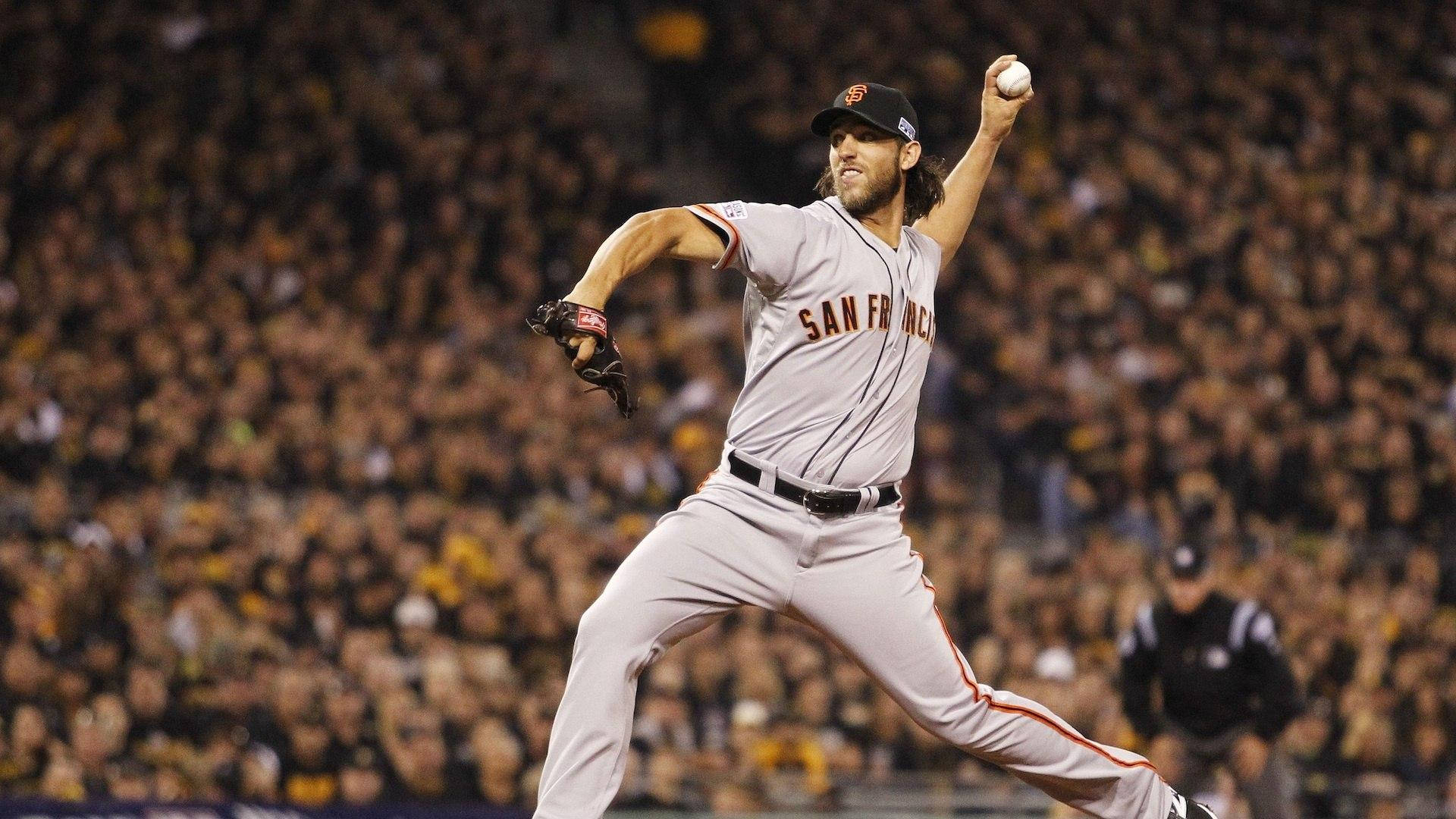 madison bumgarner 桌布 壁紙 — 一位身穿舊金山球衣的棒球投手在球場燈光下投球，背景是模糊的人群。