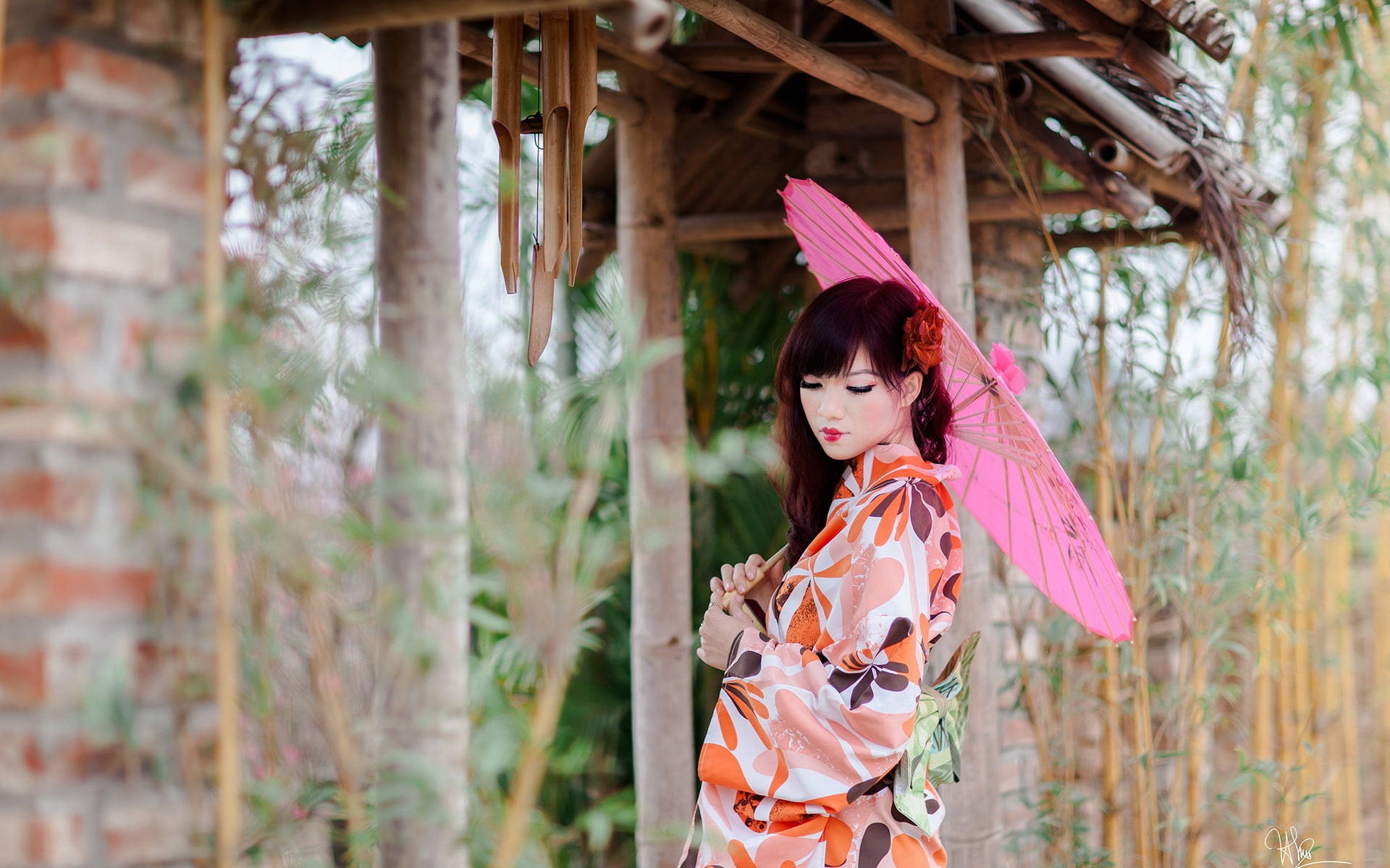 日本 桌布 壁紙 — 一位身穿花卉和服的女士在竹林環繞的竹亭下撐著粉紅色陽傘。