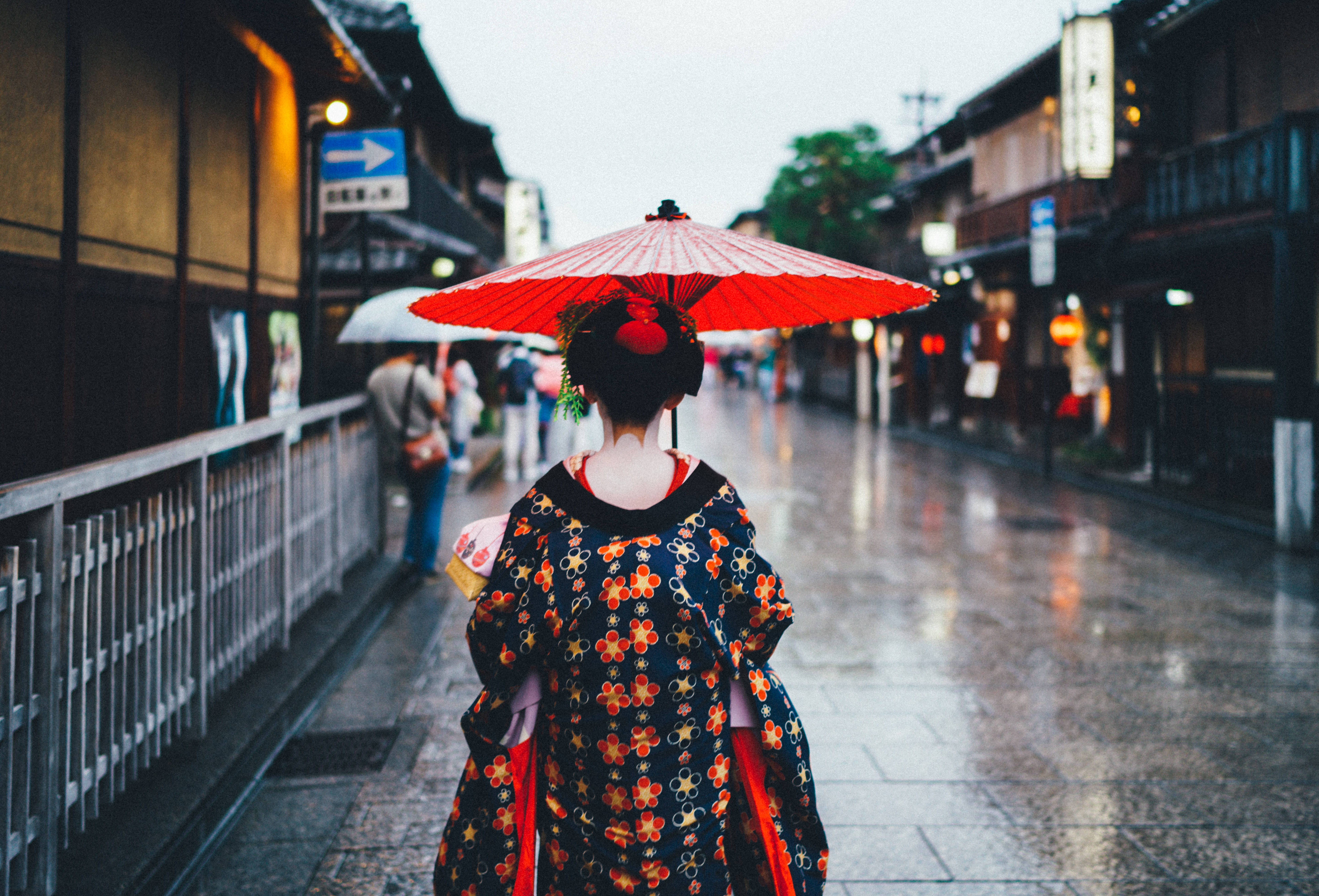 street photography 桌布 壁紙 — 一位身穿花卉和服的女士撐著紅色雨傘沿著潮濕的日本街道走遠。