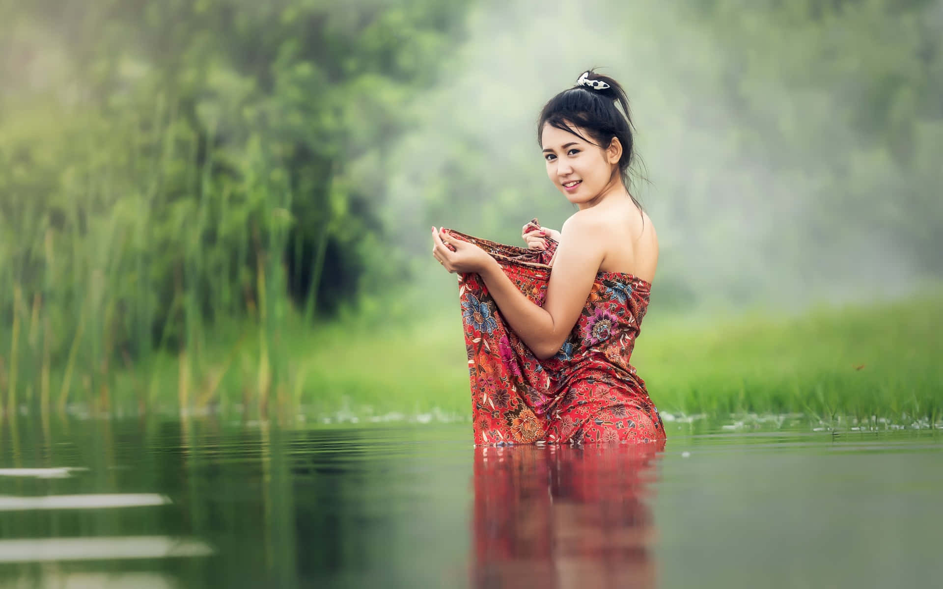 美女 桌布 壁紙 — 一位身穿花卉連衣裙的女子站在齊腰深的平靜水中，周圍是茂密的綠色蘆葦和薄霧。