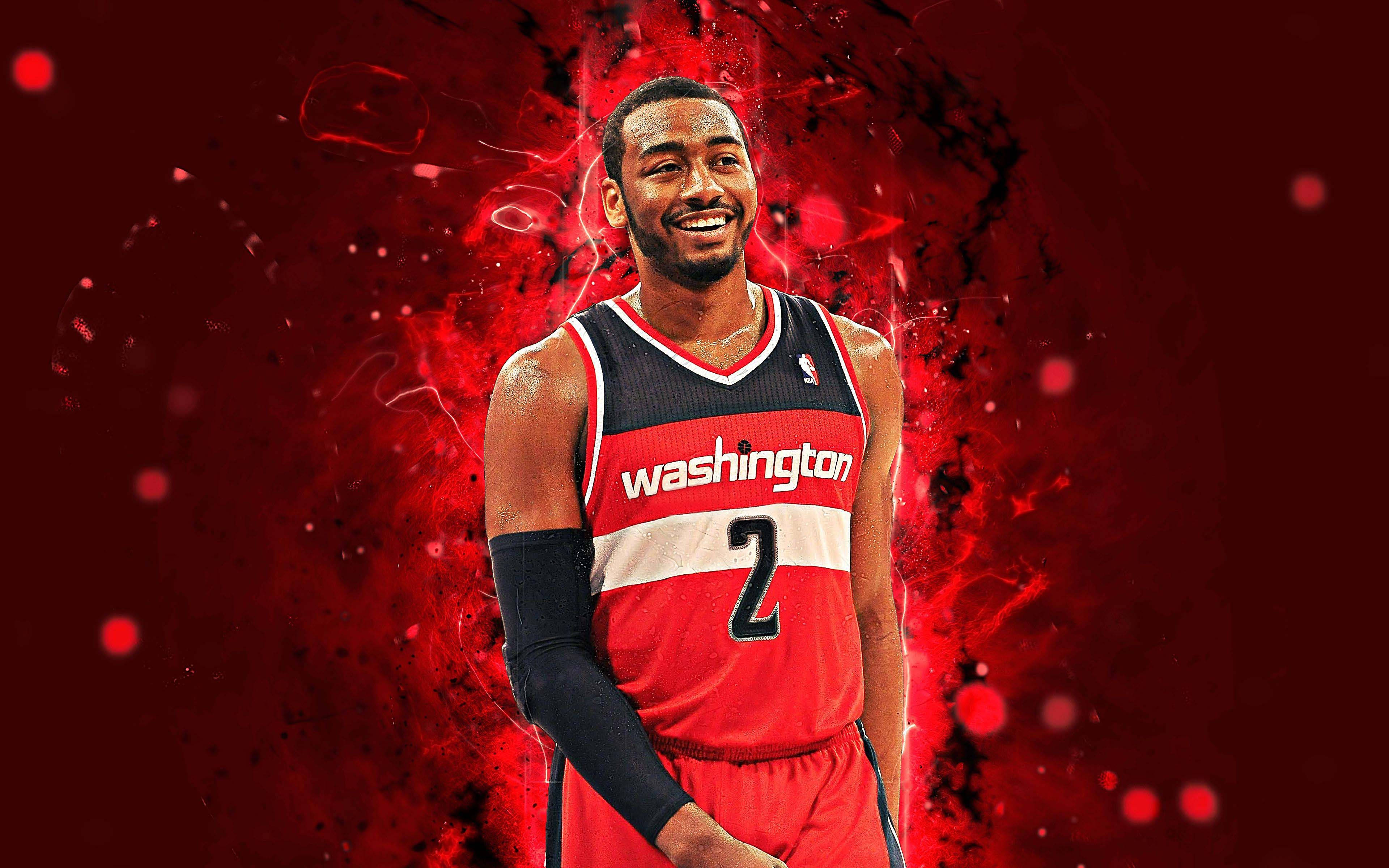 John Wall 桌布 壁紙 — 一位身穿華盛頓球衣的籃球運動員微笑著站在充滿發光粒子的鮮紅色抽象背景前。