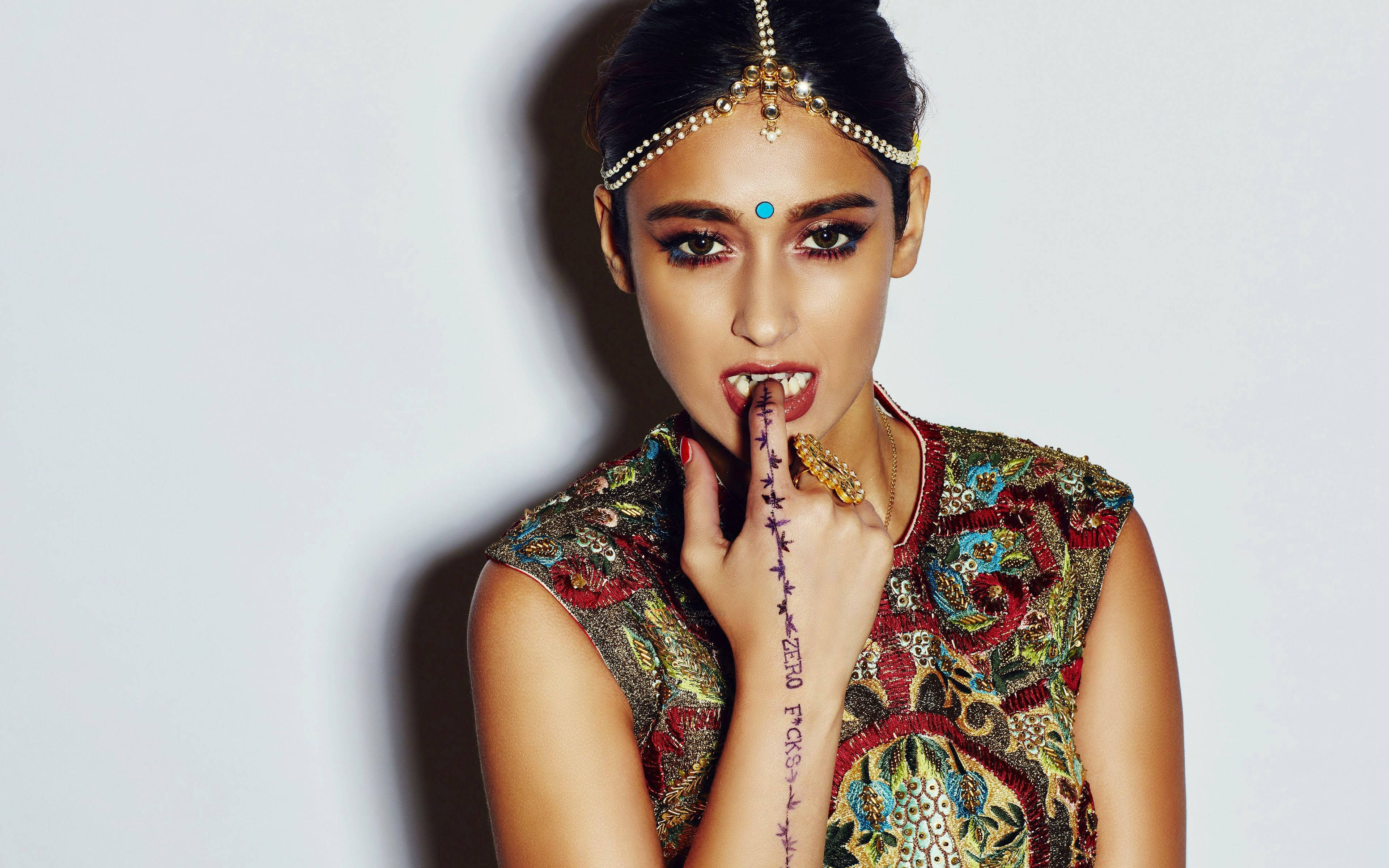 Ileana D'cruz 桌布 壁紙 — 一位身穿華麗傳統服飾、妝容大膽、手指有刺青的女性，在純白背景前擺姿勢。