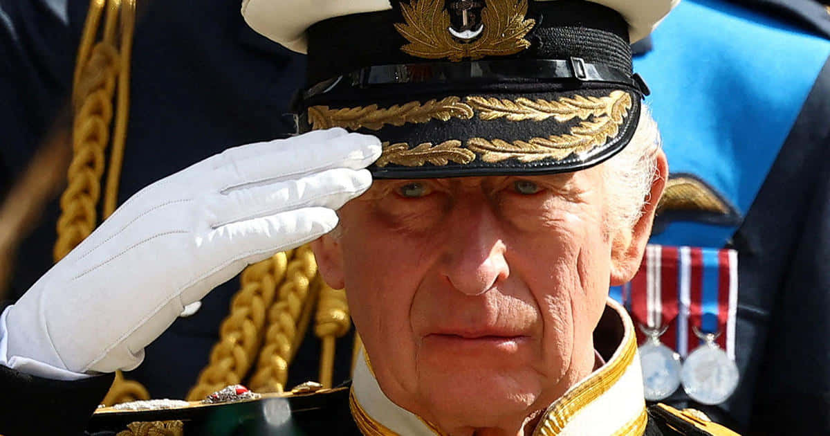 UK 桌布 壁紙 — 一位身穿華麗海軍藍制服的年長男性，戴著白手套的手敬禮，背景是金色辮帶和勳章。