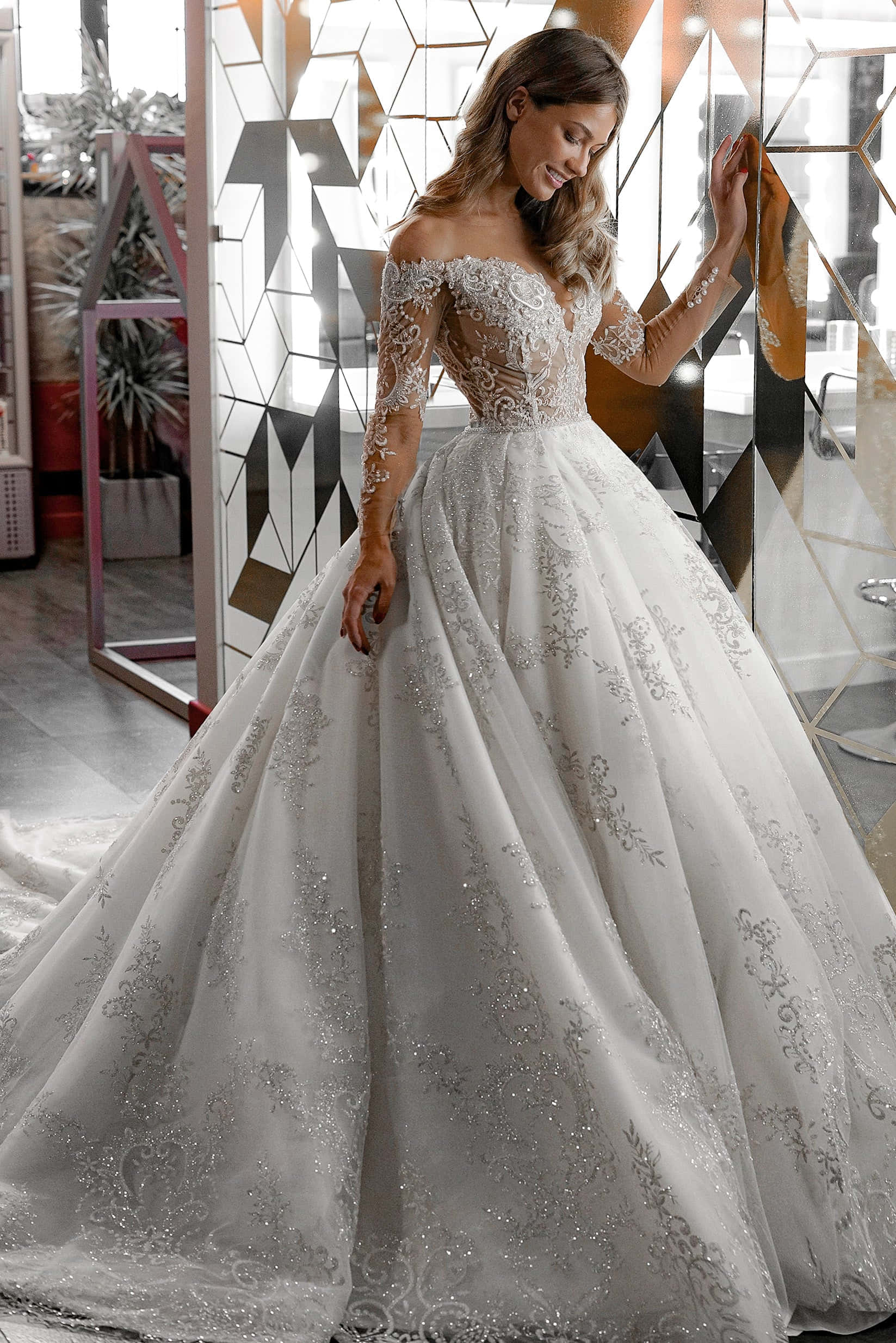 Bride's Dress 桌布 壁紙 — 一位身穿華麗白色舞會禮服、綴有蕾絲和亮片的新娘，優雅地站在幾何鏡面牆旁。