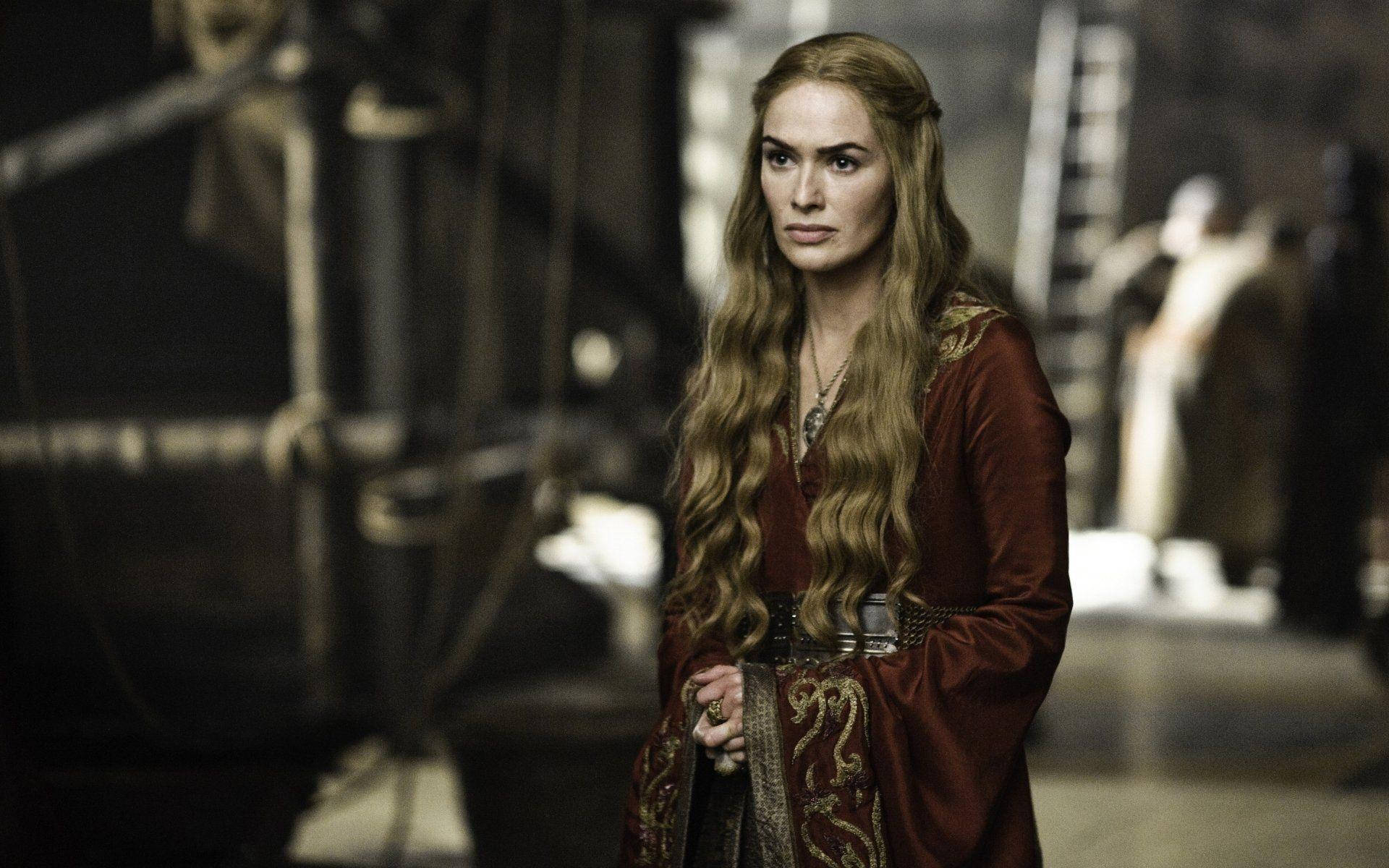 cersei lannister 桌布 壁紙 — 一位身穿華麗紅色中世紀長袍的女性，在昏暗的工業風格環境中莊嚴站立，周圍有繩索和金屬結構。