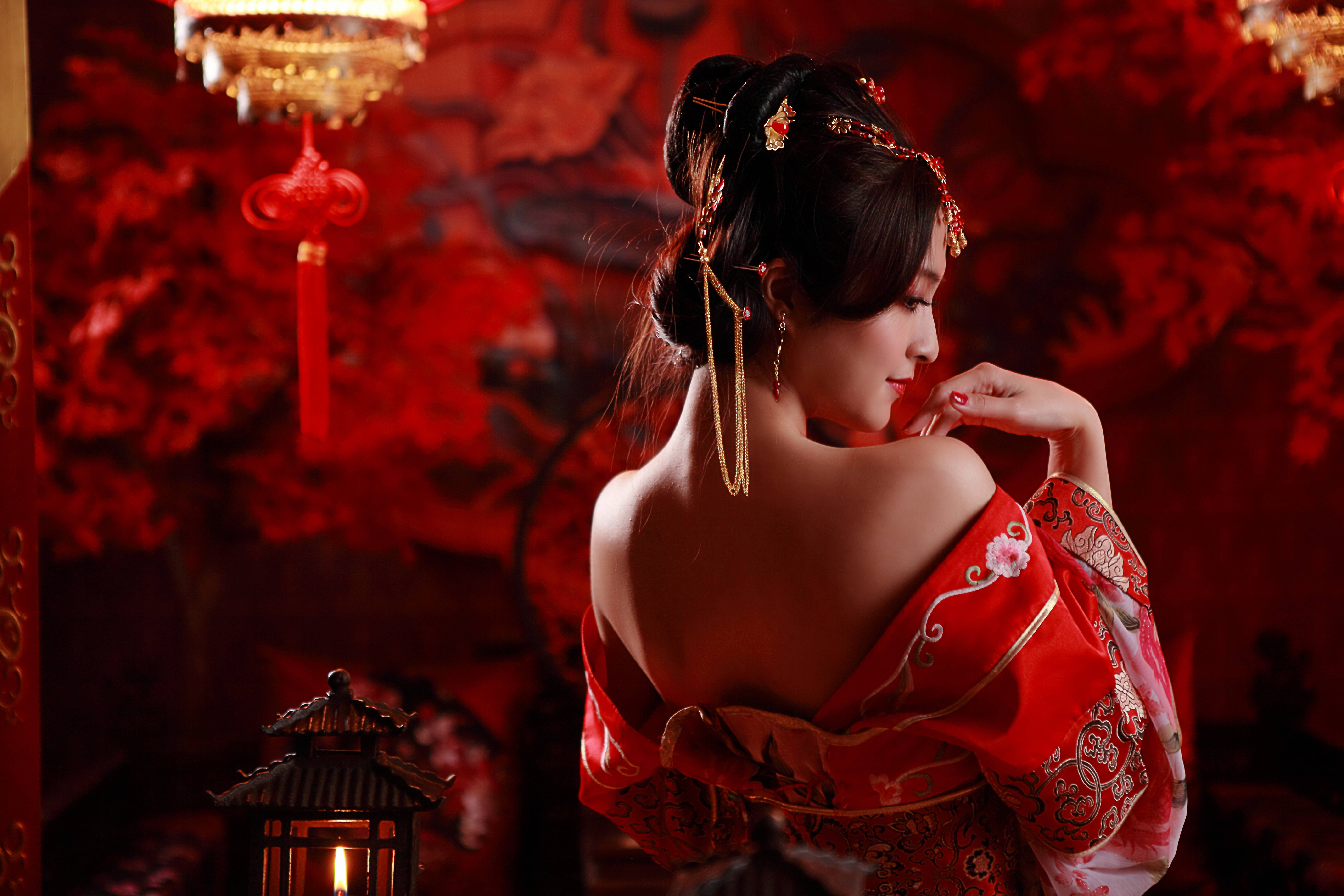 美女 桌布 壁紙 — 一位身穿華麗紅色傳統服飾的女性，在一個掛有燈籠和花卉圖案的華麗房間中若有所思地凝視著。