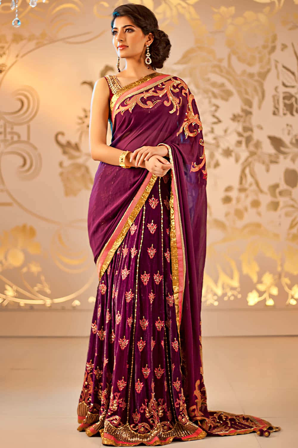 Saree 桌布 壁紙 — 一位身穿華麗紫色天鵝絨紗麗、飾有金色和粉紅色刺繡的女性，優雅地站在金色花卉壁紙前。