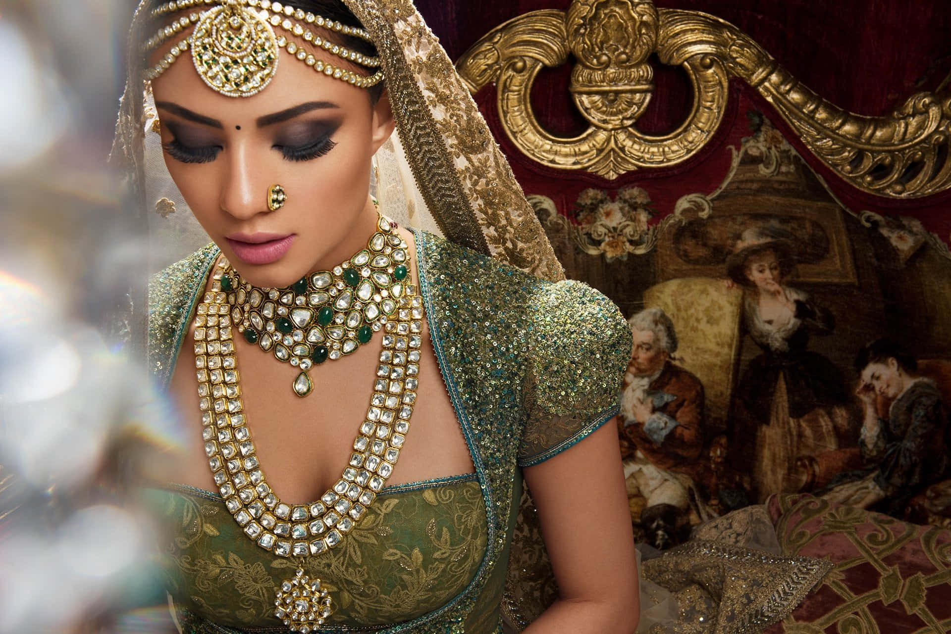 Bride 桌布 壁紙 — 一位身穿華麗綠色和金色傳統服飾、佩戴珠寶的女性，在裝飾華麗的豪華房間中低頭凝視。