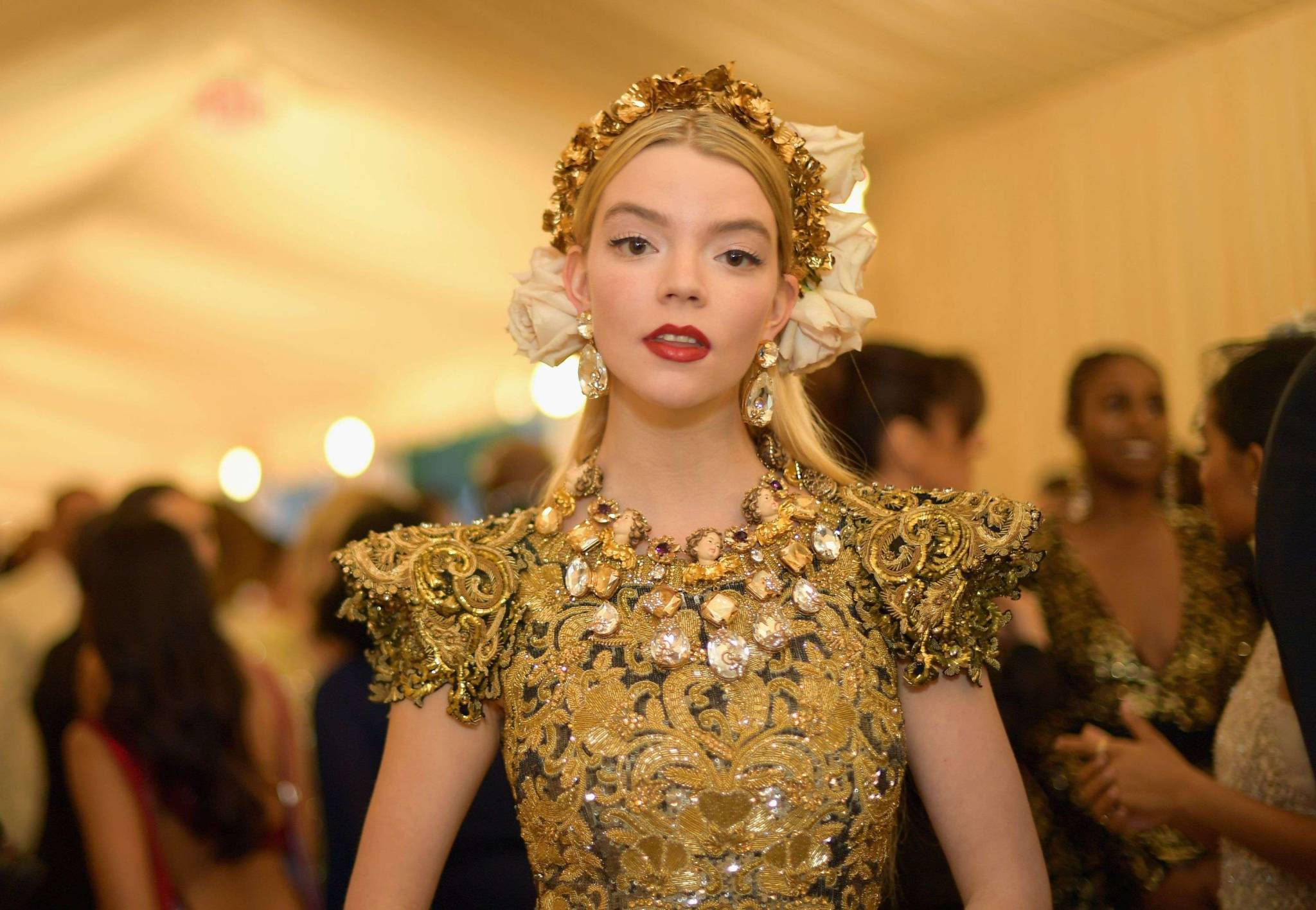 Anya 桌布 壁紙 — 一位身穿華麗金色和黑色禮服、頭戴花卉頭飾的女性在迷人的室內活動中擺姿勢。