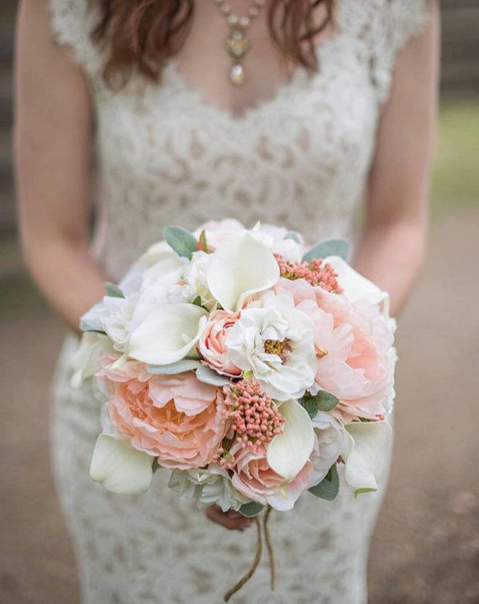 Bride 桌布 壁紙 — 一位身穿蕾絲禮服的新娘手持一束由蜜桃色牡丹、白色馬蹄蓮和珊瑚漿果組成的豐盛花束。