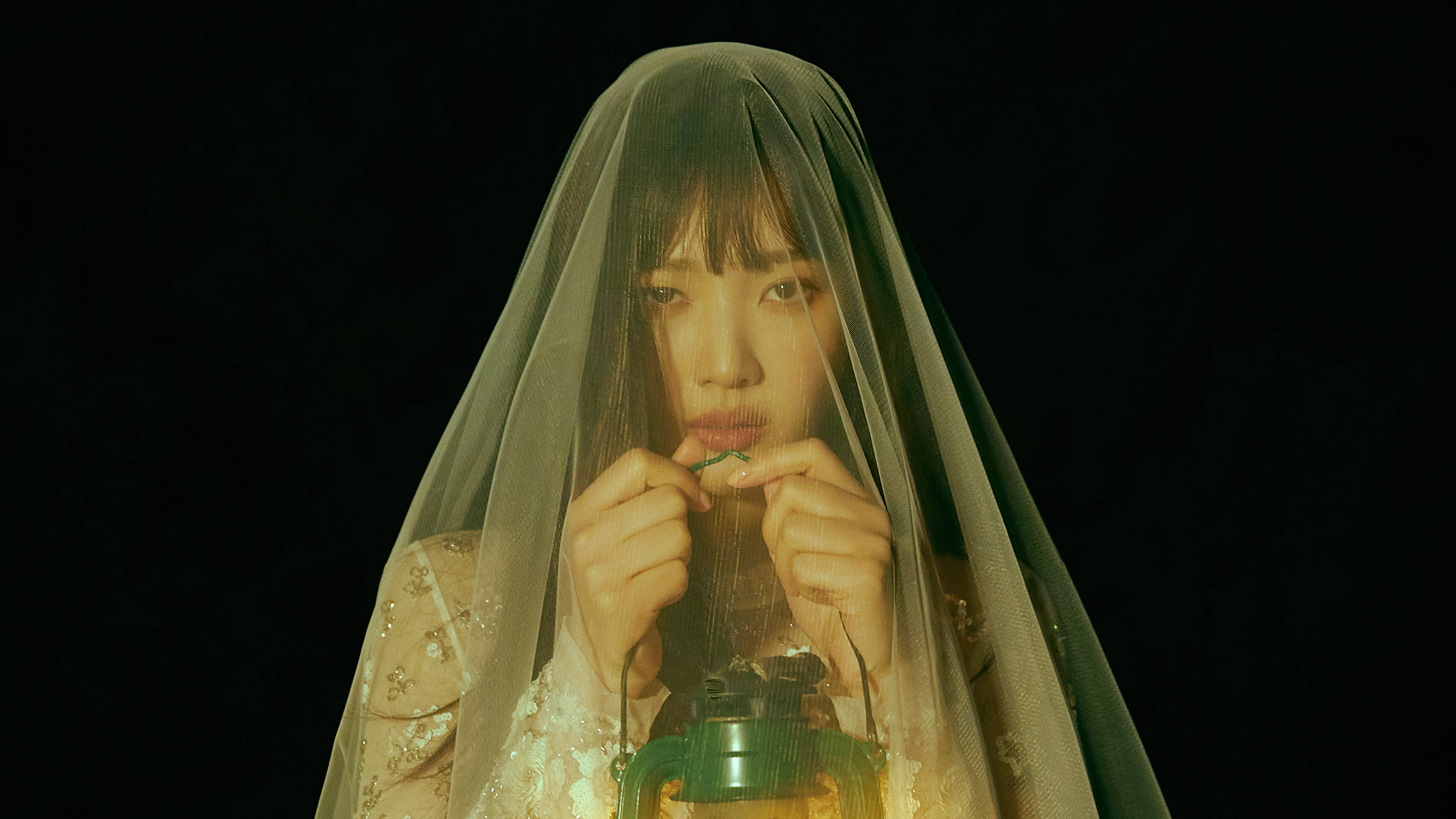 Velvet 桌布 壁紙 — 一位身穿薄紗面紗的女子，在黑色背景下手持發光的燈籠，雙手輕柔地調整燈芯。