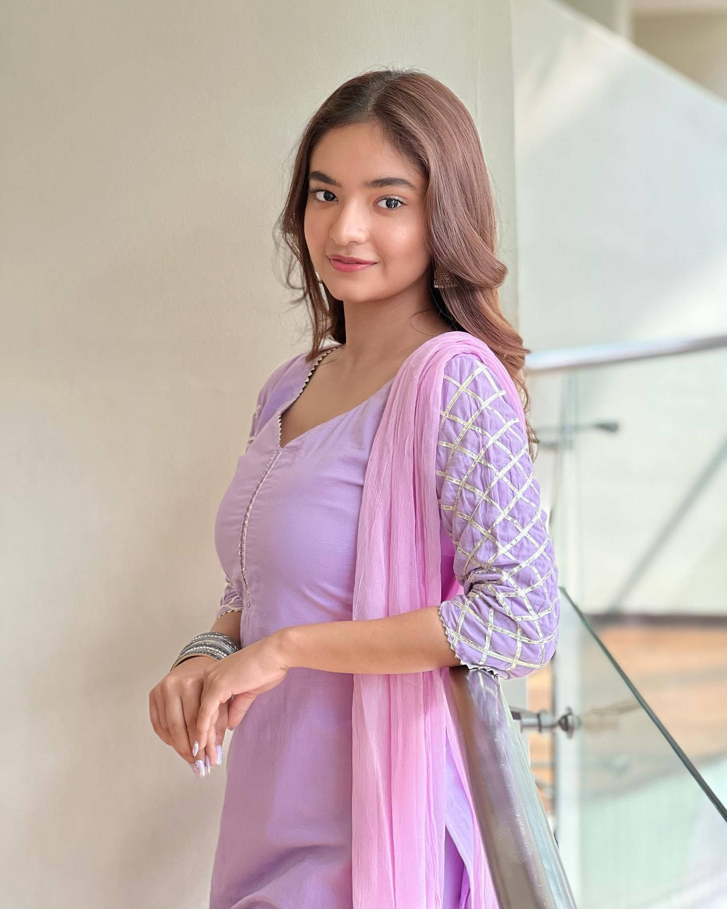 Indian 桌布 壁紙 — 一位身穿薰衣草色傳統服飾的年輕女性，在室內靠著玻璃欄杆微笑。