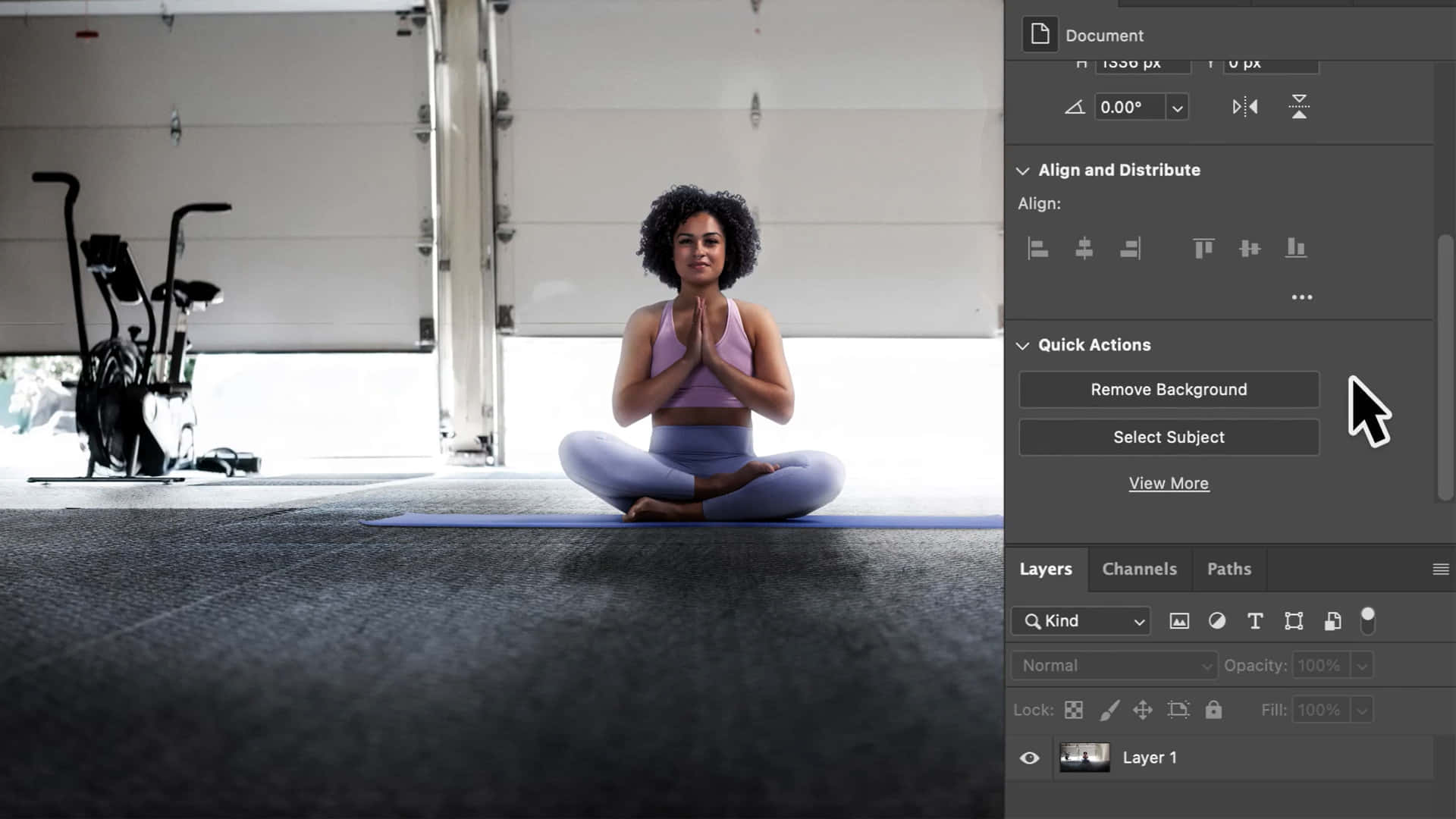 photoshop 桌布 壁紙 — 一位身穿薰衣草色運動服的女士在車庫的藍色瑜伽墊上盤腿而坐，雙手合十呈祈禱姿勢，身後可見一輛健身腳踏車。