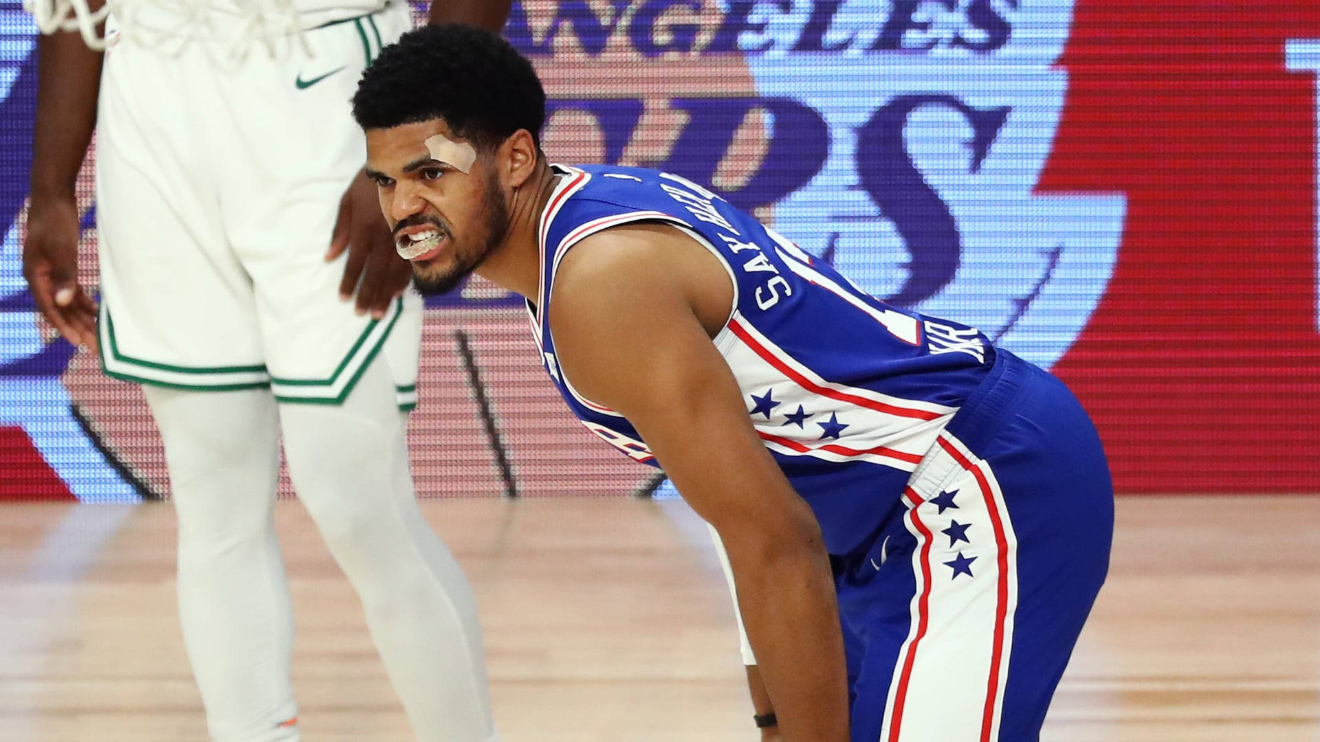 NBA 桌布 壁紙 — 一位身穿藍白球衣的籃球運動員在球場上彎腰向前，神情專注。