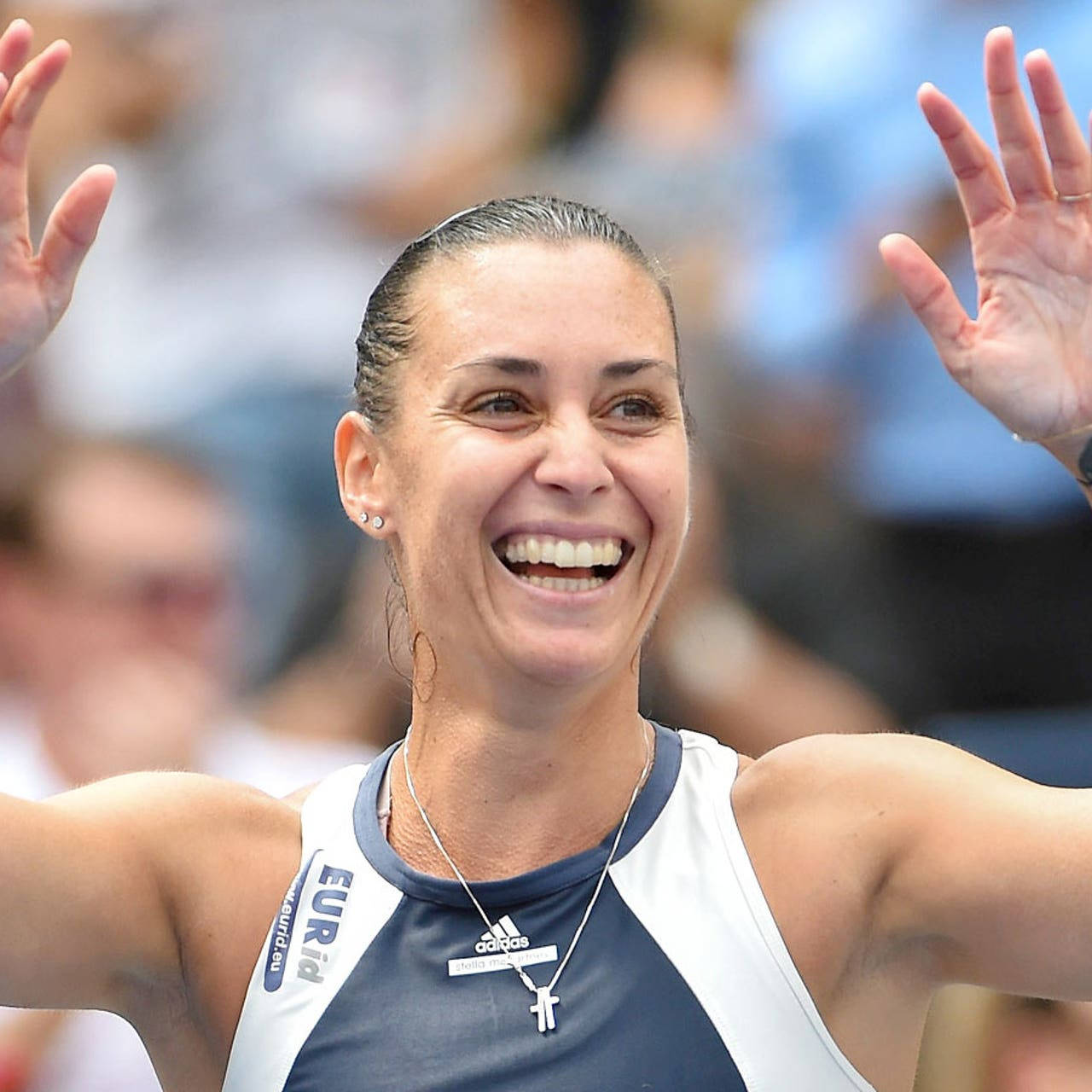Tennis 桌布 壁紙 — 一位身穿藍白運動上衣的快樂女運動員，笑容燦爛，高舉雙手慶祝。