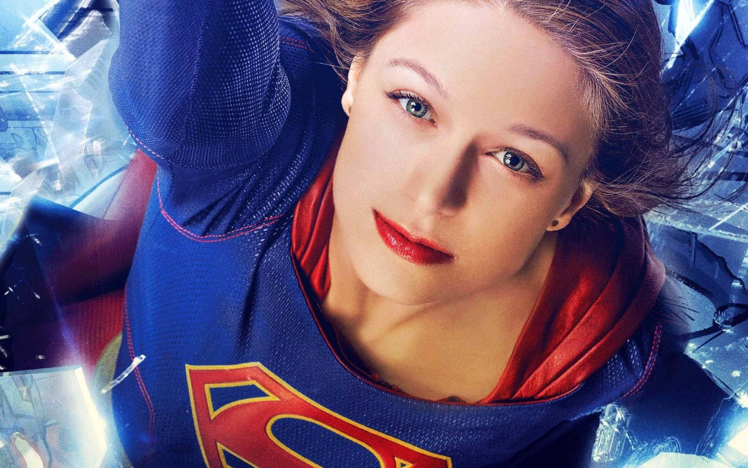 Melissa 桌布 壁紙 — 一位身穿藍紅配色服裝、帶有超人標誌的女超級英雄，以堅定的目光衝破碎玻璃。
