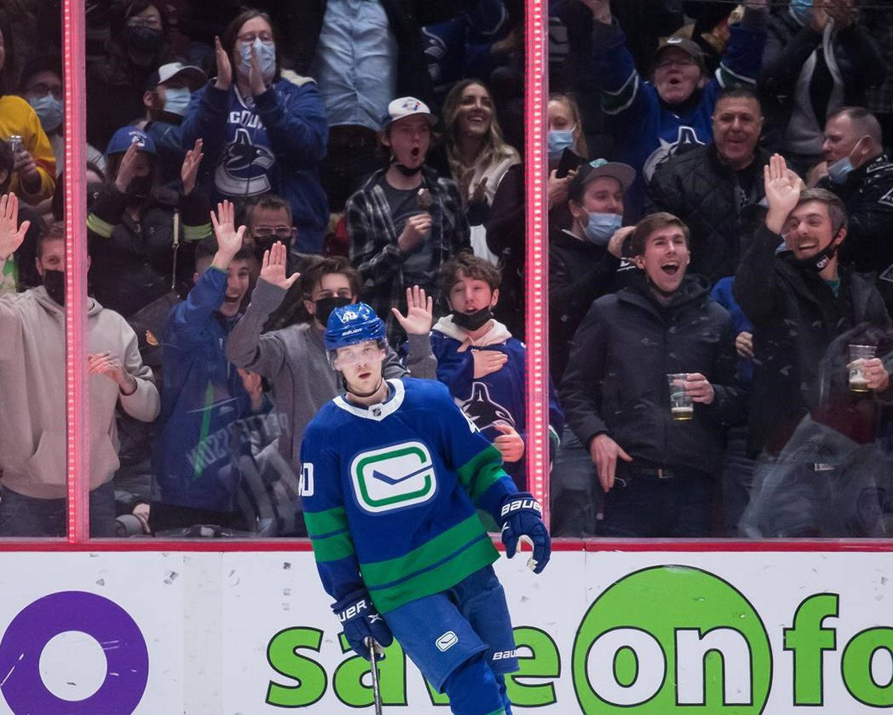 hockey 桌布 壁紙 — 一位身穿藍綠色球衣的溫哥華加人隊（Vancouver Canucks）冰球運動員，在場館玻璃後面向歡呼的球迷揮手。