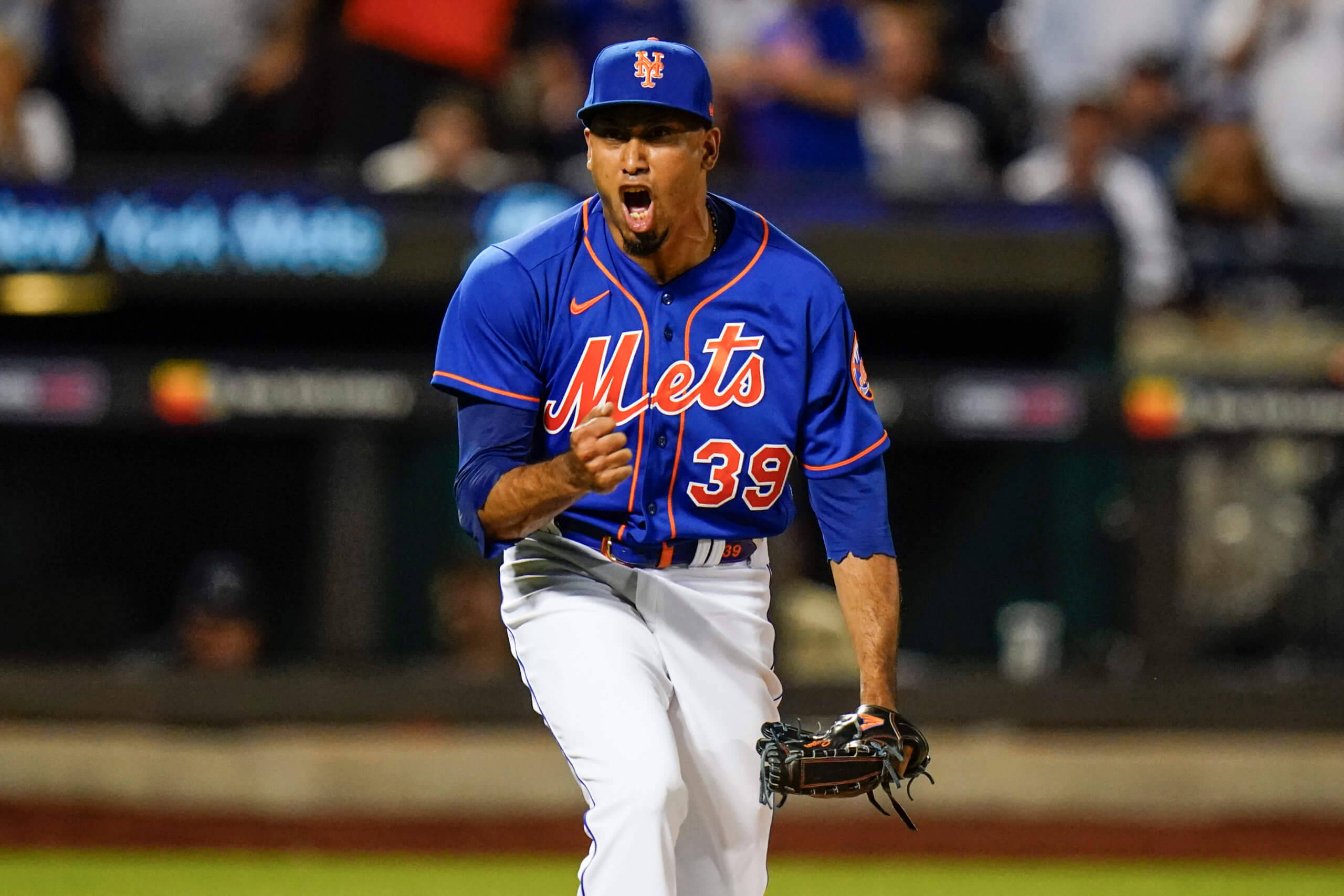 New York Mets 桌布 壁紙 — 一位身穿藍色39號球衣的Mets棒球選手在夜間比賽中，在球場燈光下激情咆哮。