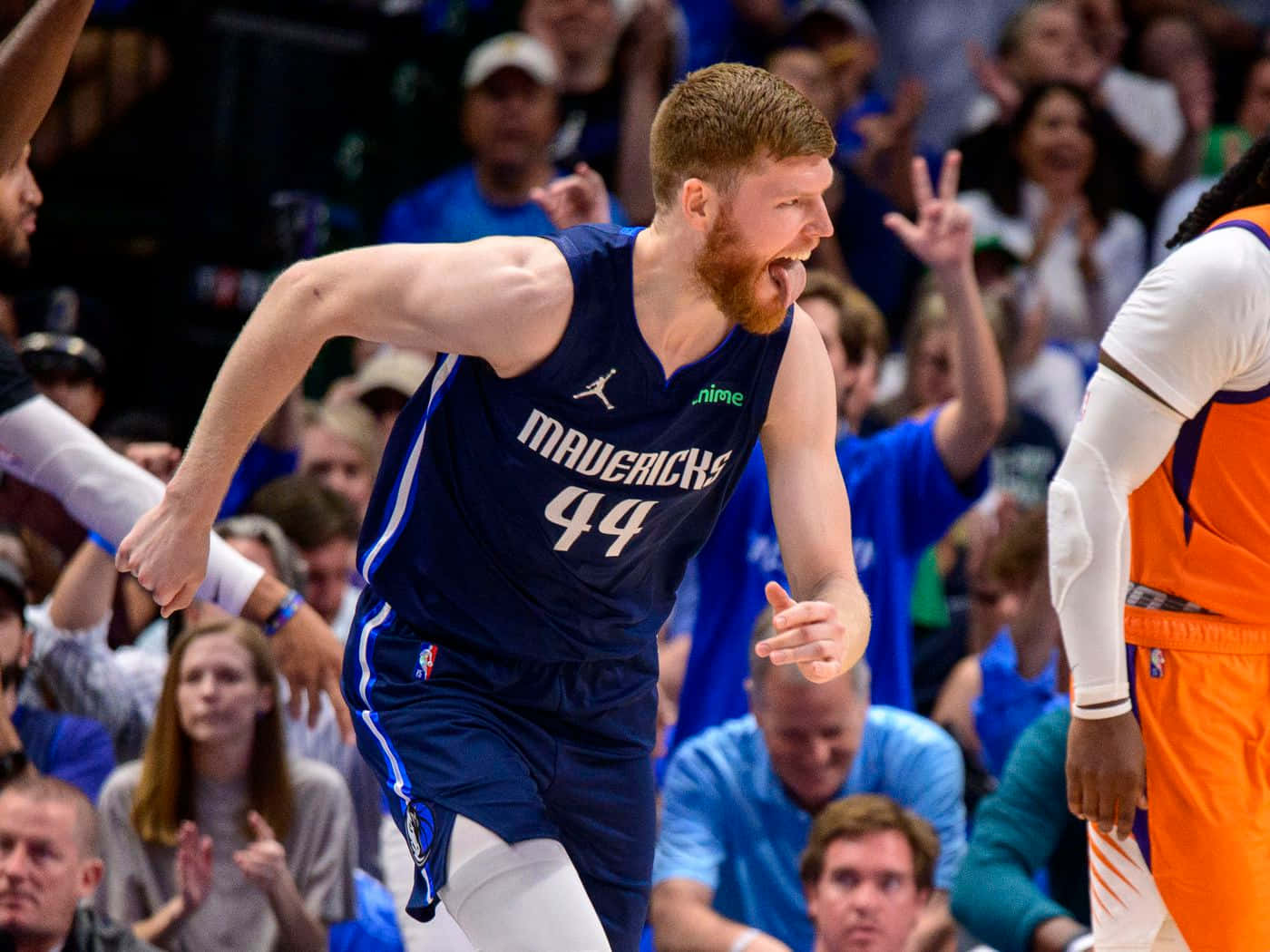 NBA標誌 桌布 壁紙 — 一位身穿藍色44號球衣的達拉斯獨行俠籃球球員在比賽中激烈咆哮，背景中球迷歡呼。