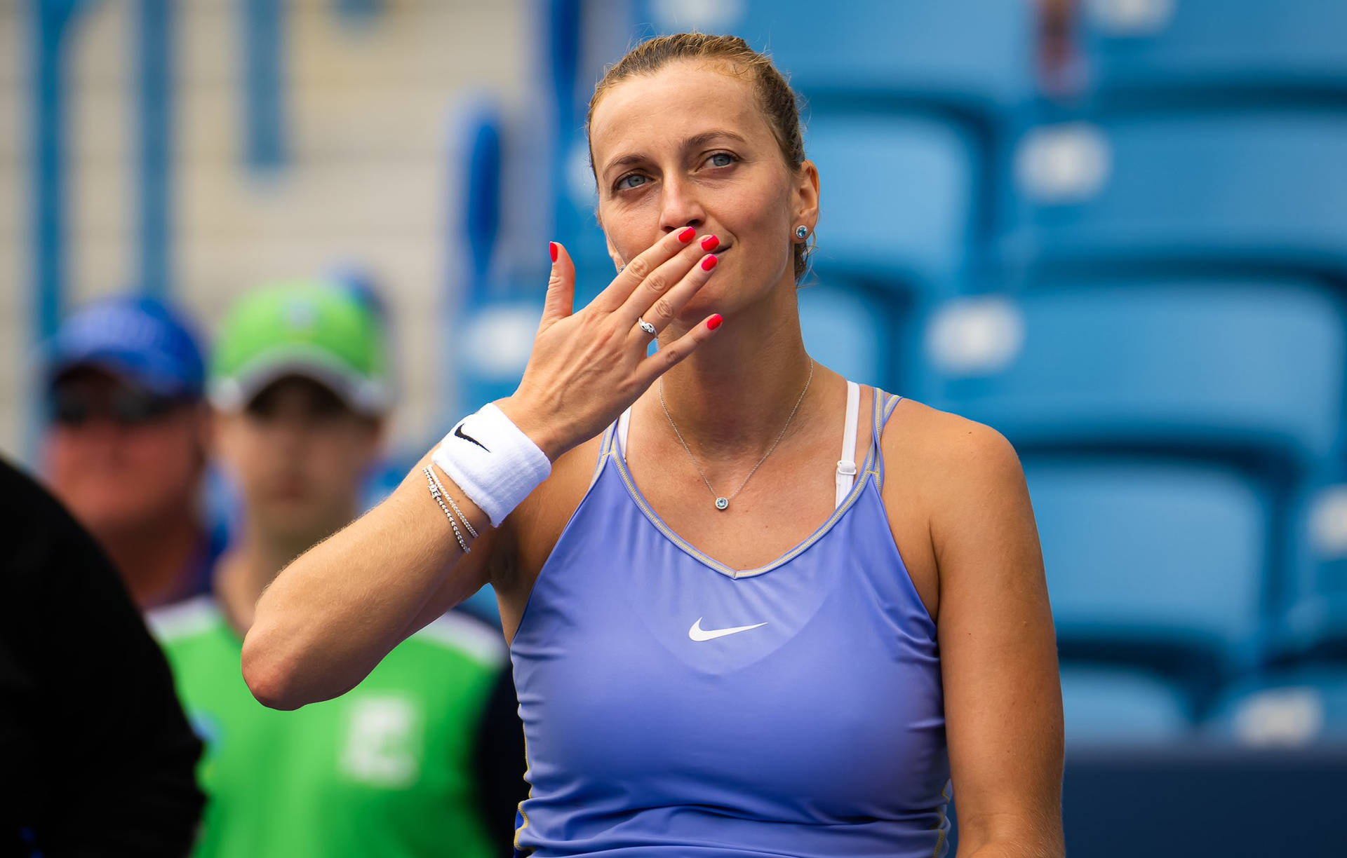 Nike 桌布 壁紙 — 一位身穿藍色Nike上衣的女網球選手在比賽中微笑並用手遮住嘴巴。