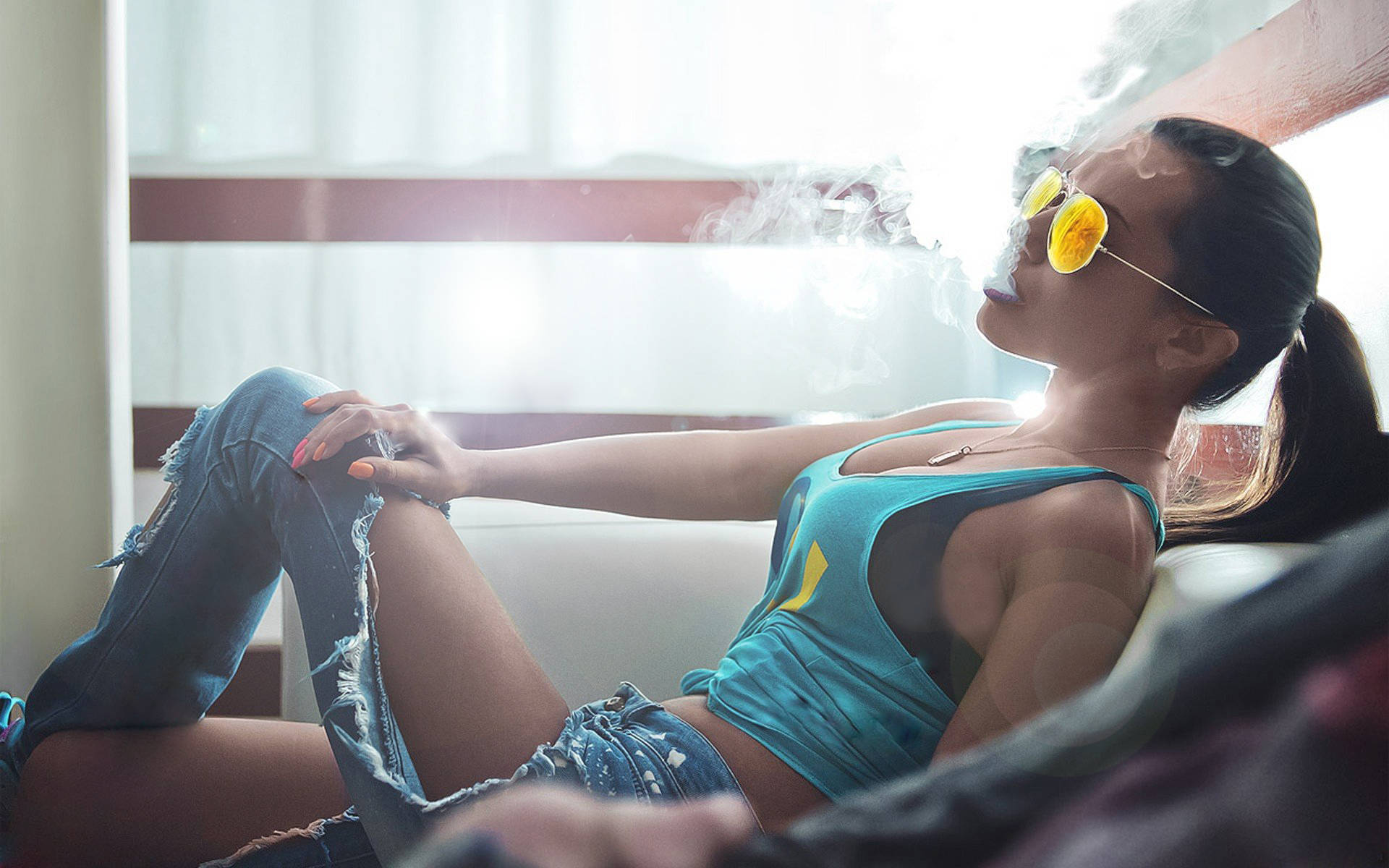 抽菸 桌布 壁紙 — 一位身穿藍色上衣和破洞牛仔褲的女性，戴著黃色太陽眼鏡，躺在沙發上呼出煙霧。