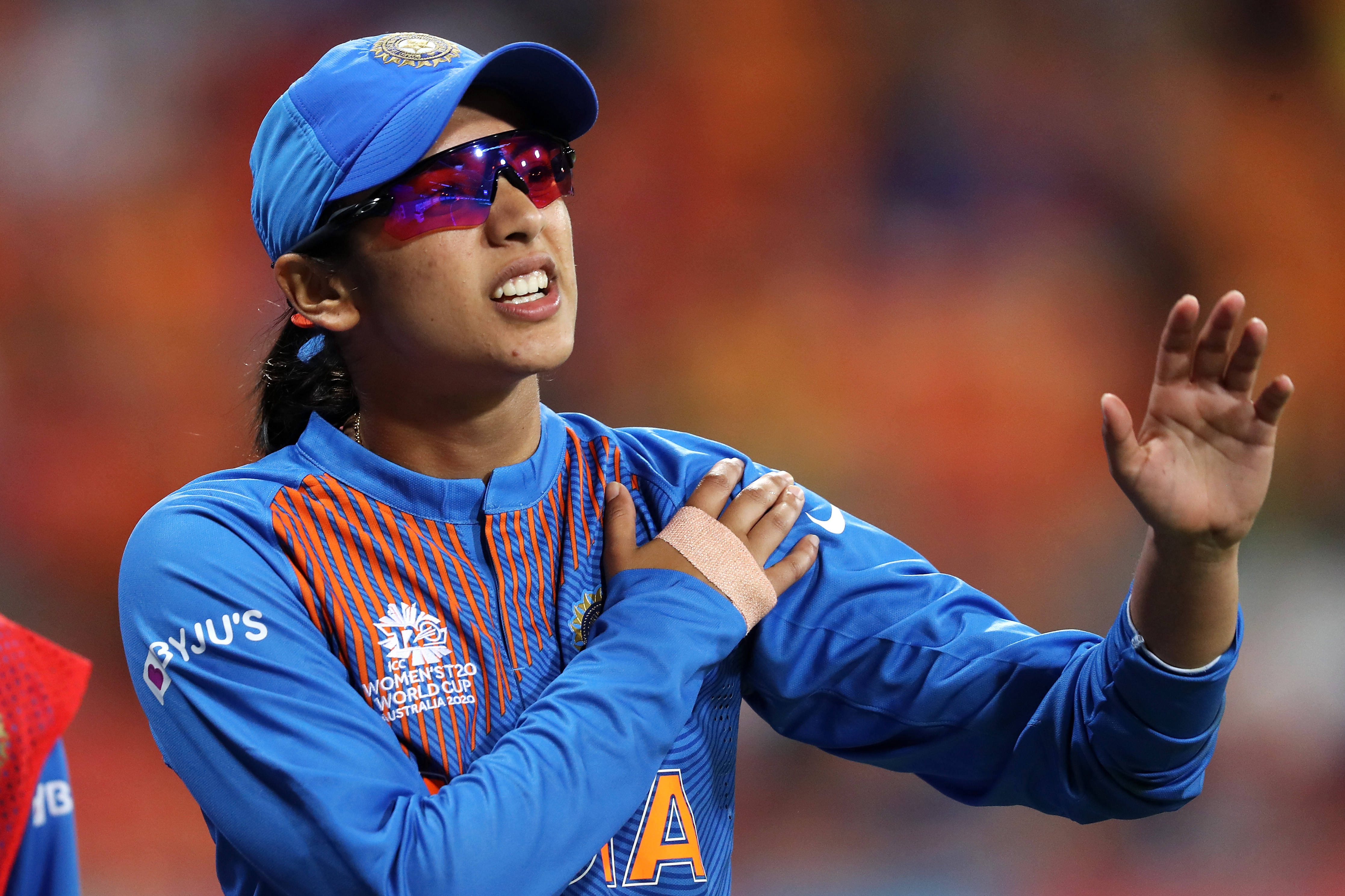 Smriti Mandhana 桌布 壁紙 — 一位身穿藍色制服和太陽眼鏡的女板球運動員在比賽中熱情高舉雙手慶祝。