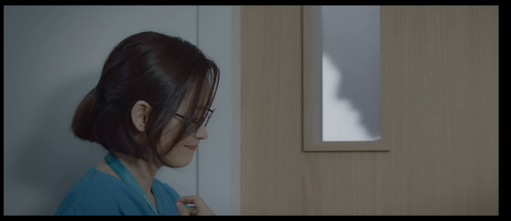 Playlist 桌布 壁紙 — 一位身穿藍色制服的女士站在門旁，身後牆上投射出陰影。