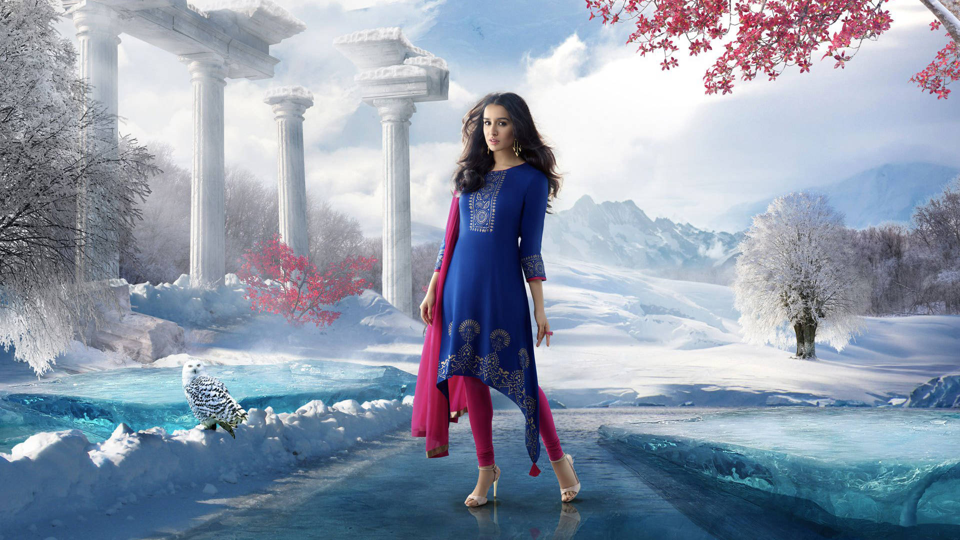 Shraddha Kapoor 桌布 壁紙 — 一位身穿藍色和粉紅色傳統服飾的女性，在雪景中走過古老遺跡和結冰的河流，旁邊有一隻雪鴞。