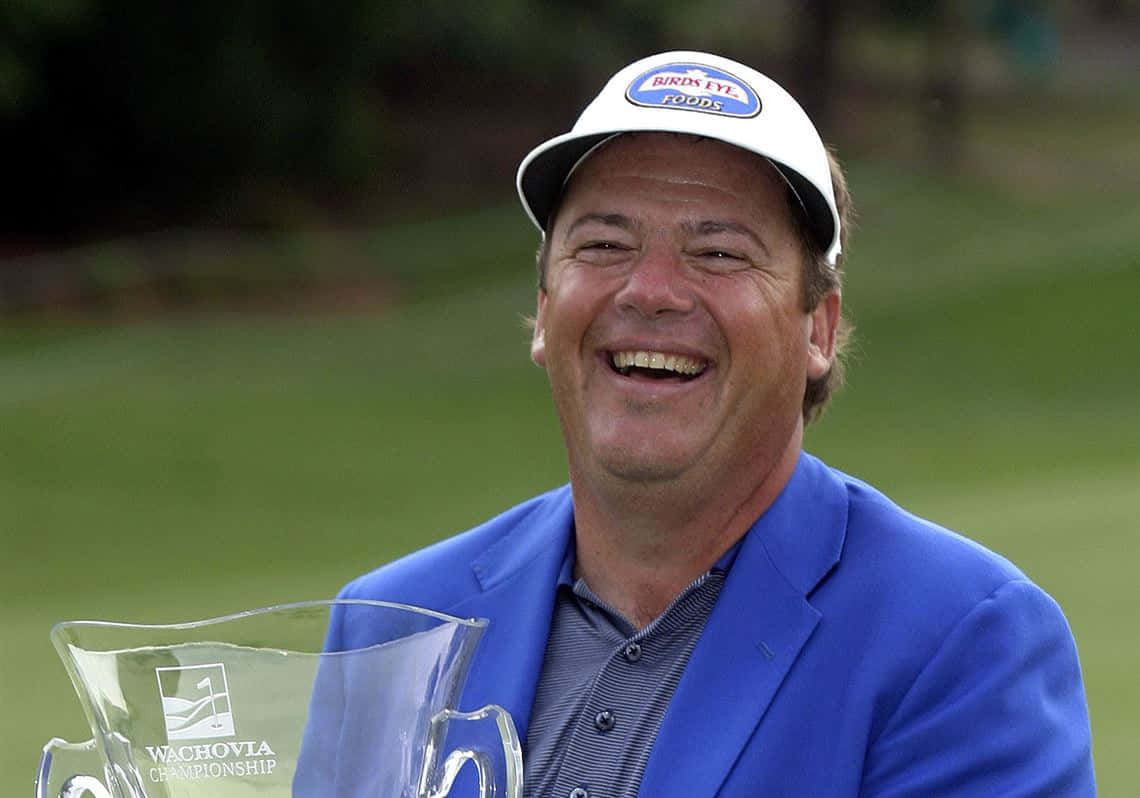 Trophy 桌布 壁紙 — 一位身穿藍色夾克的高爾夫球手，在綠色球場上手持清晰的Wachovia Championship獎盃，笑容滿面。
