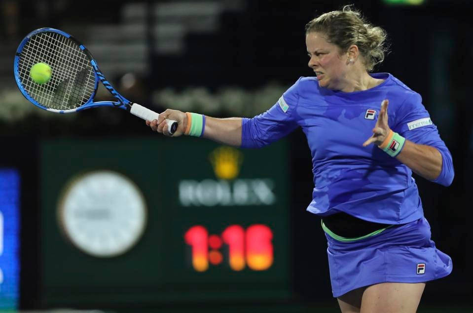 Tennis 桌布 壁紙 — 一位身穿藍色服裝的女網球選手在明亮的體育場燈光下，於夜間比賽中揮拍擊打黃色網球。