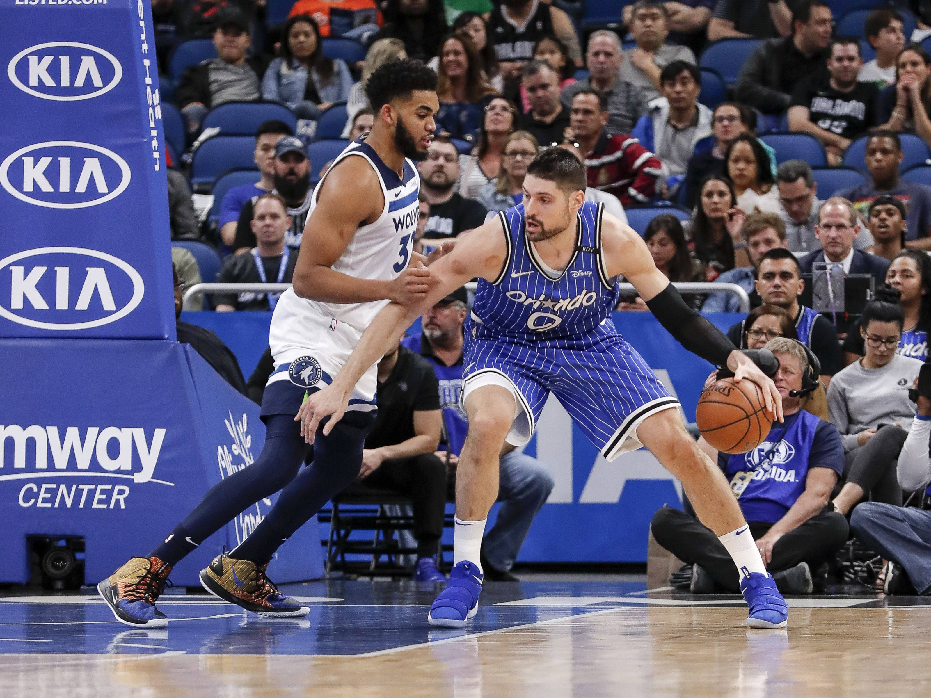 NBA 桌布 壁紙 — 一位身穿藍色條紋球衣的籃球運動員在現場比賽中運球，同時被一位身穿白色球衣的對手緊密防守。