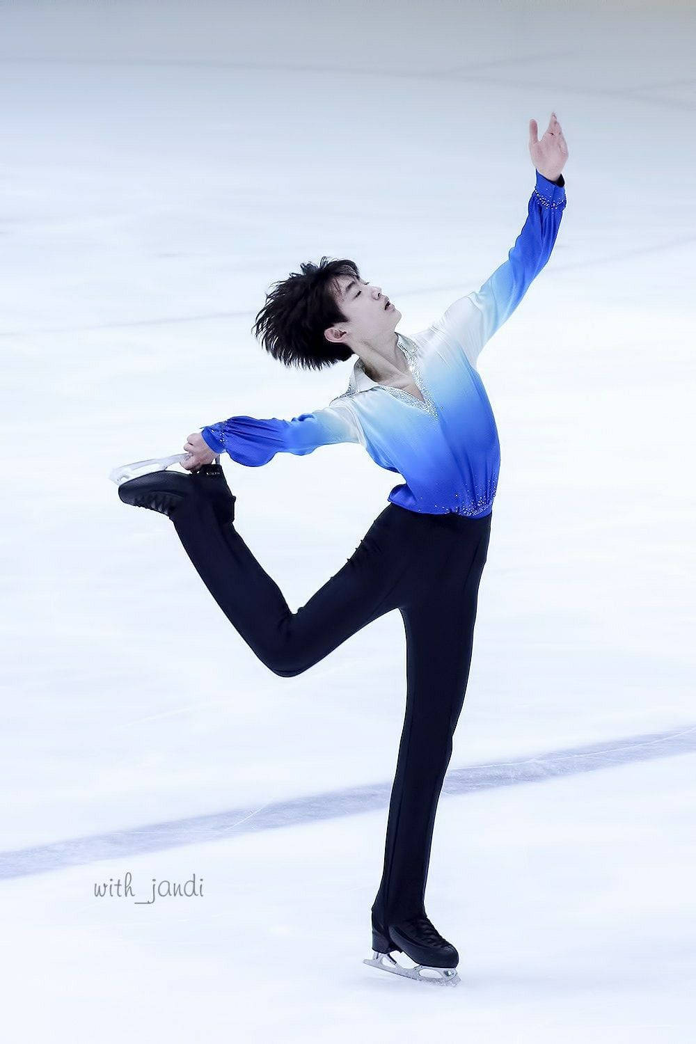 Ice Skating 桌布 壁紙 — 一位身穿藍色漸層服裝的男性花式滑冰運動員在潔淨的冰場上旋轉時，優雅地用一隻冰鞋保持平衡。