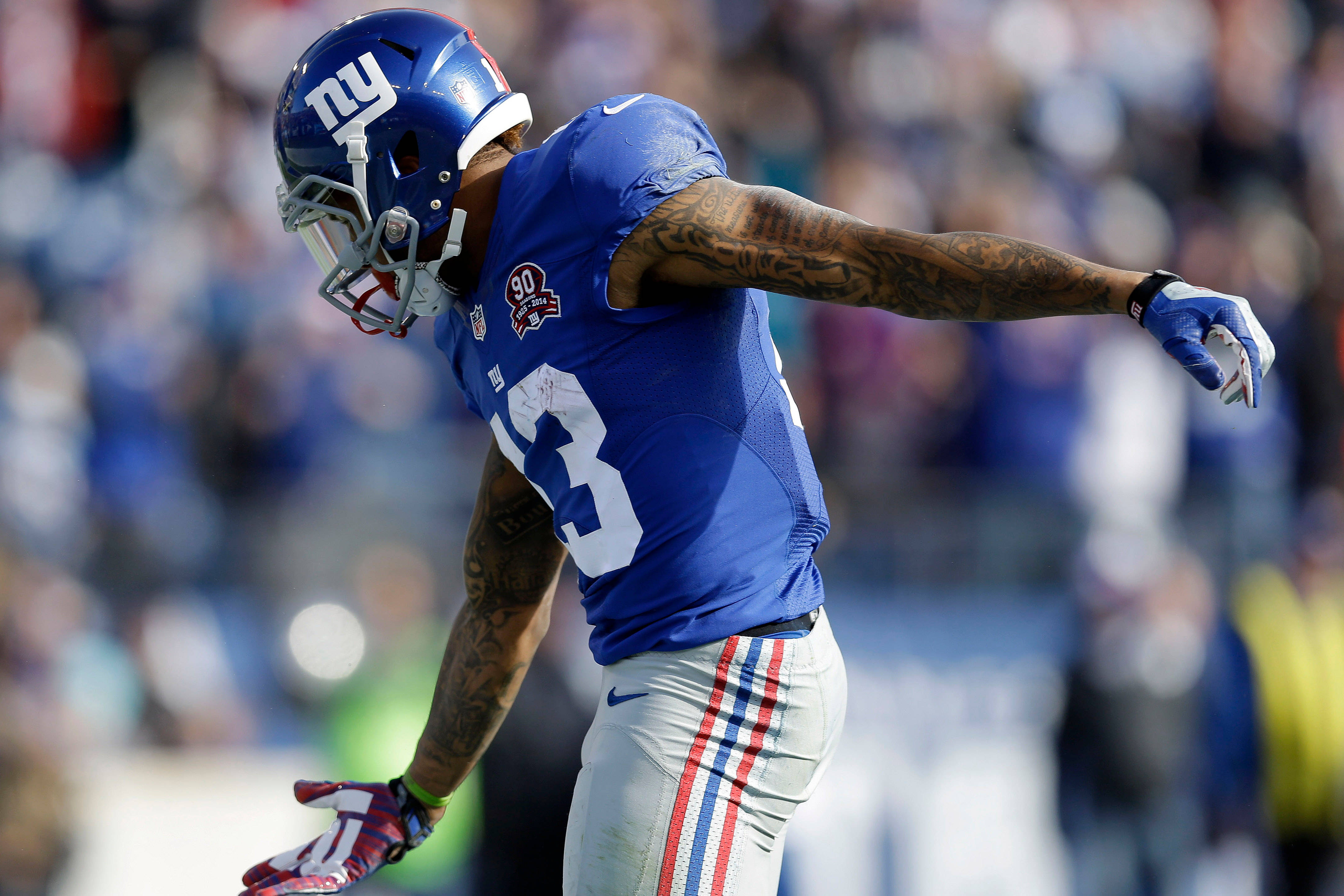 Odell 桌布 壁紙 — 一位身穿藍色球衣和頭盔的紐約巨人隊美式足球員在陽光明媚的球場上張開雙臂慶祝。