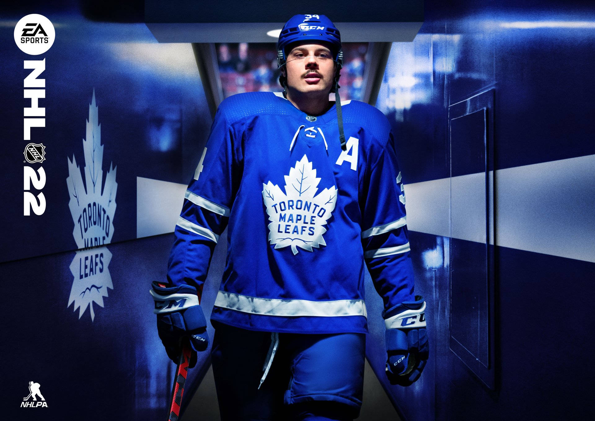 Cool Hockey 桌布 壁紙 — 一位身穿藍色球衣的多倫多楓葉冰球球員自信地站在光線昏暗的隧道中，牆上印有球隊標誌。