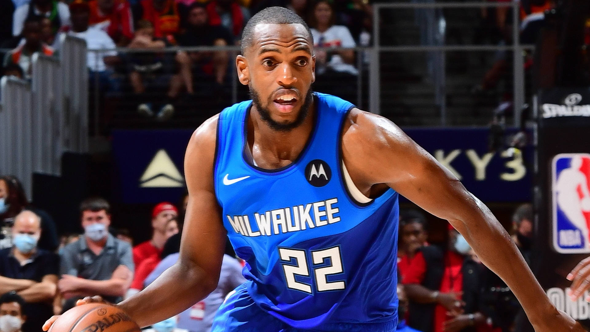 Khris Middleton 桌布 壁紙 — 一位身穿藍色球衣的密爾瓦基公鹿籃球運動員在比賽中激烈運球，背景有觀眾。