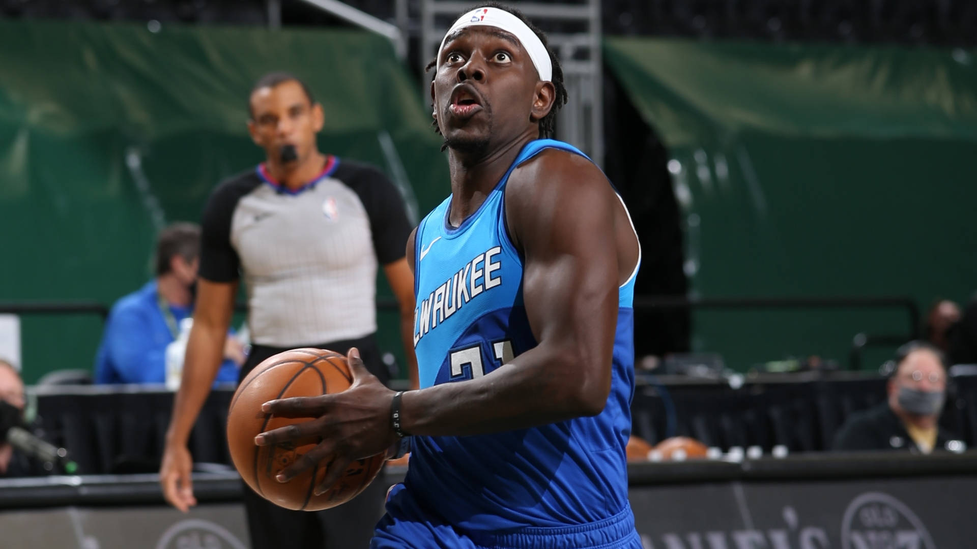 Jrue Holiday 桌布 壁紙 — 一位身穿藍色球衣的密爾瓦基公鹿籃球運動員在比賽中專注地運球。