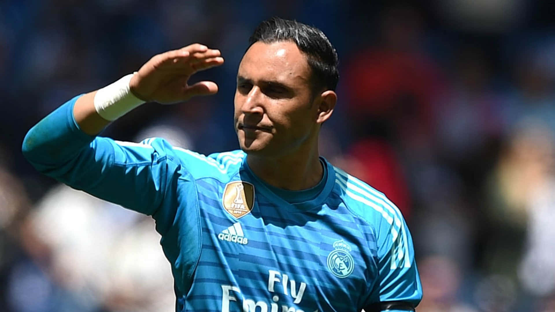 Keylor Navas 桌布 壁紙 — 一位身穿藍色皇家馬德里球衣的足球守門員在明亮的體育場燈光下向球迷揮手。