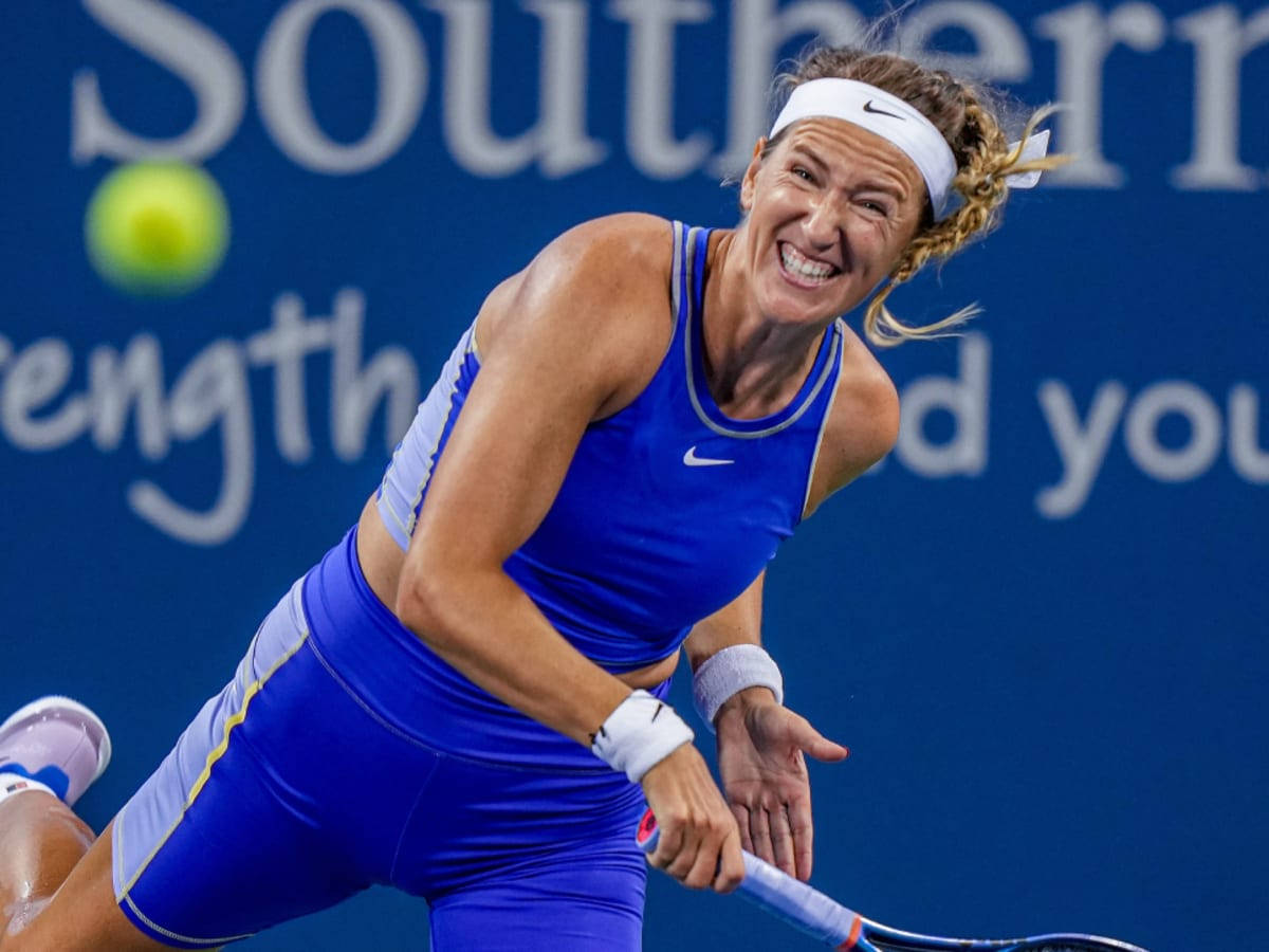 Athletic 桌布 壁紙 — 一位身穿藍色裝備的女網球運動員，帶著強烈的專注力向前衝刺，揮拍擊向一個黃色網球。